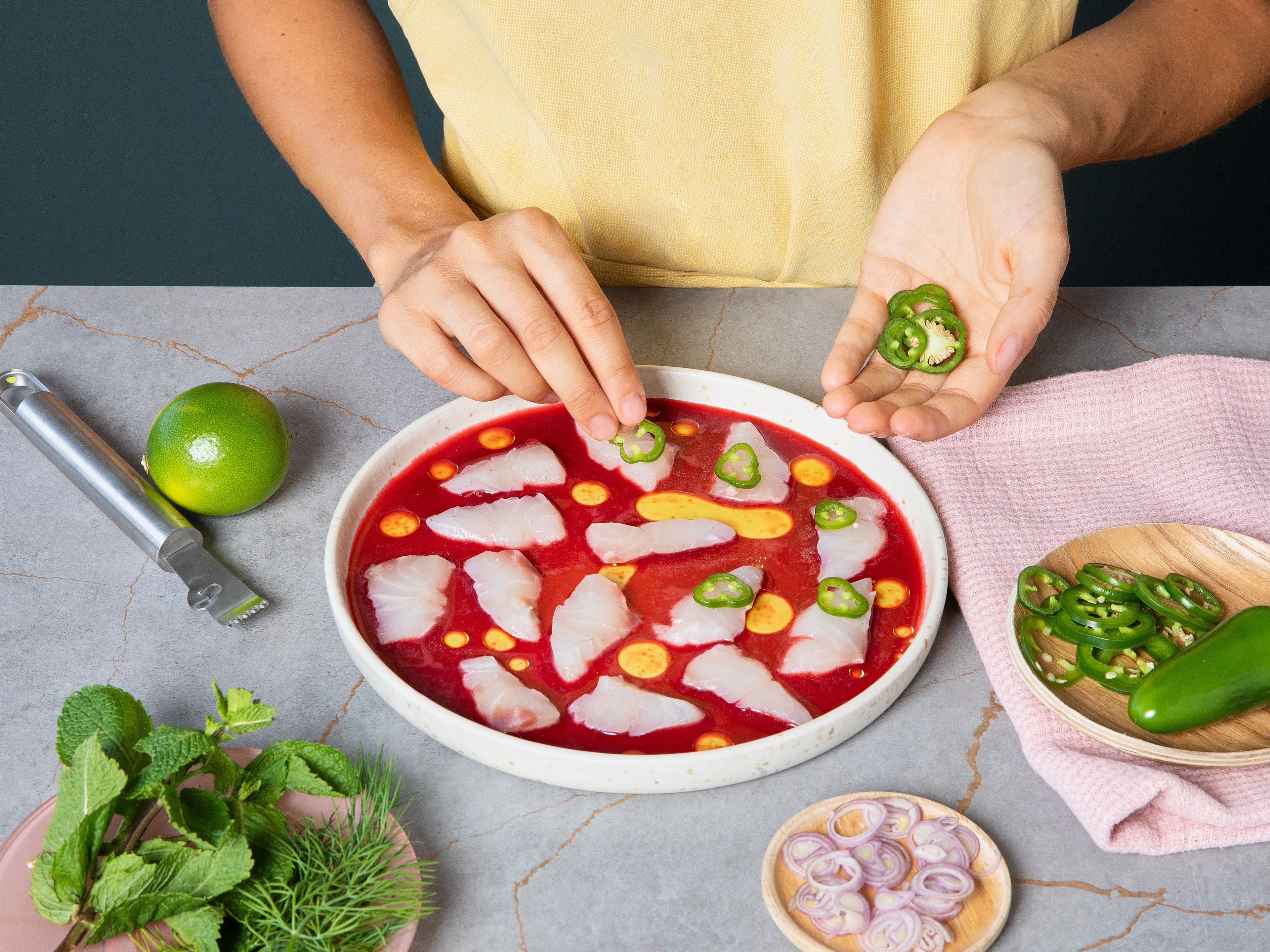 Pour vinaigrette onto a plate and drizzle with olive oil. Arrange fish on top and top each slice with a jalapeño slice, shallots, and capers. Garnish with mint, dill and lime zest. Season with flaky salt and serve immediately.