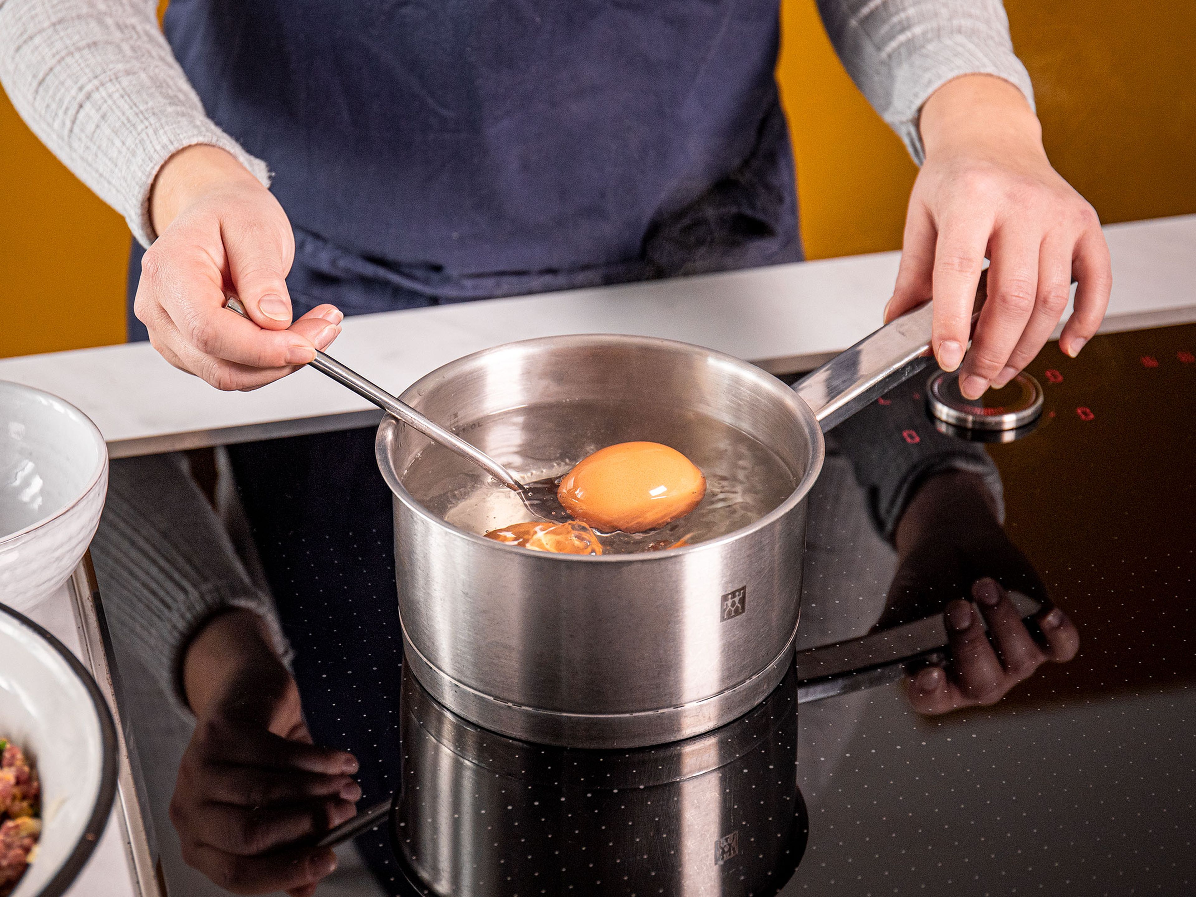 Einen kleinen Topf mit Wasser auf großer Stufe  erhitzen. Sobald das Wasser kocht, die restlichen Eier hineingeben und 6 1/2 Min. kochen lassen. Abtropfen lassen und zum Abkühlen unter fließendes kaltes Wasser halten. Nun die Eier schälen.
