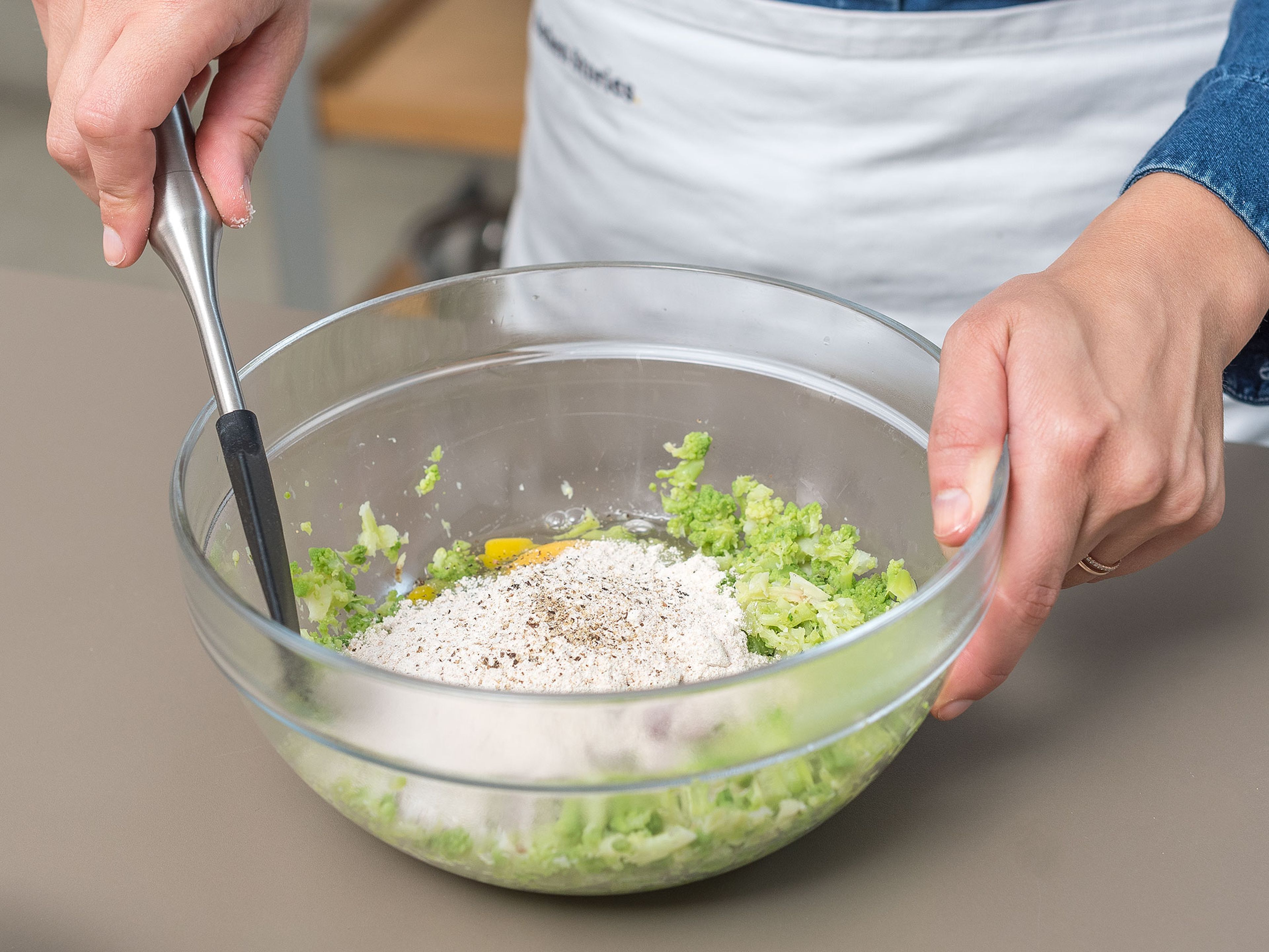 Finely chop scallions. Mash Romanesco in a bowl. Add eggs, chopped scallions, whole wheat flour, salt, and pepper, and mix until a sticky batter forms.