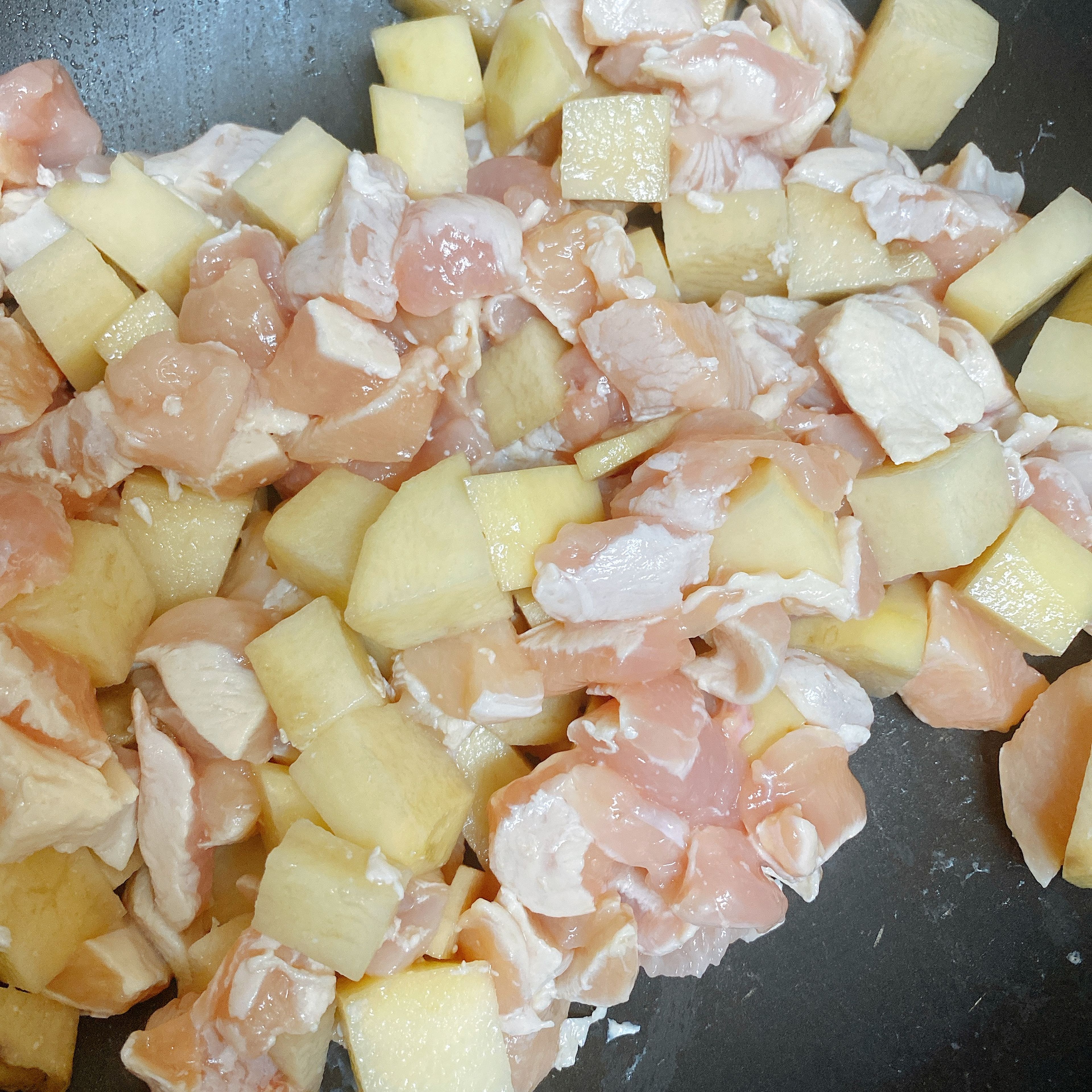 Turn the stove on to high. Add oil to the wok. When it’s heated, fry the potato and chicken for a minute.