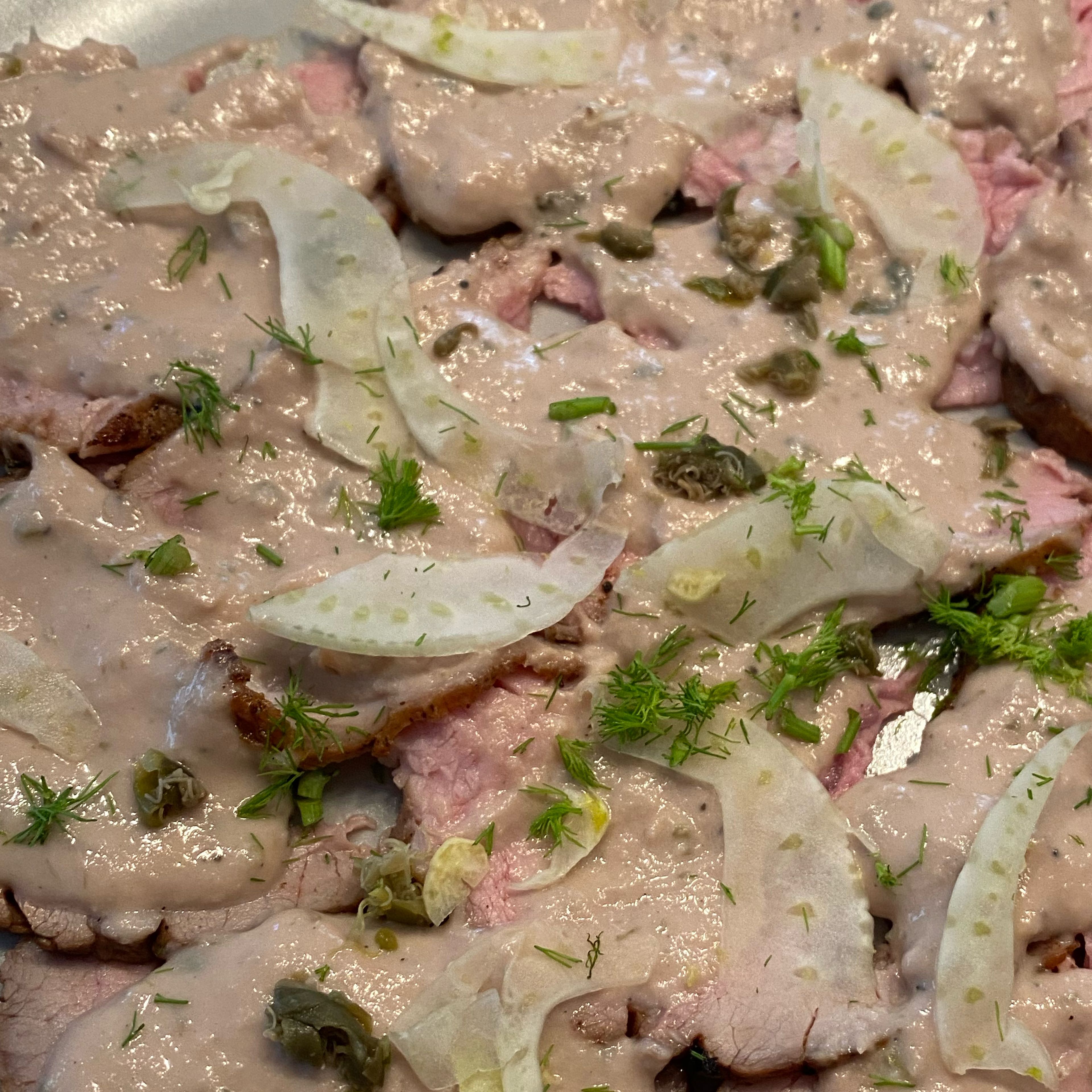 Verteilen Sie den gehobelten Fenchel auf dem Vitello Tonnato. Die restlichen Kapern und das Grün der Fenchelknolle nach Belieben drüber geben. Mit Pfeffer abschmecken.