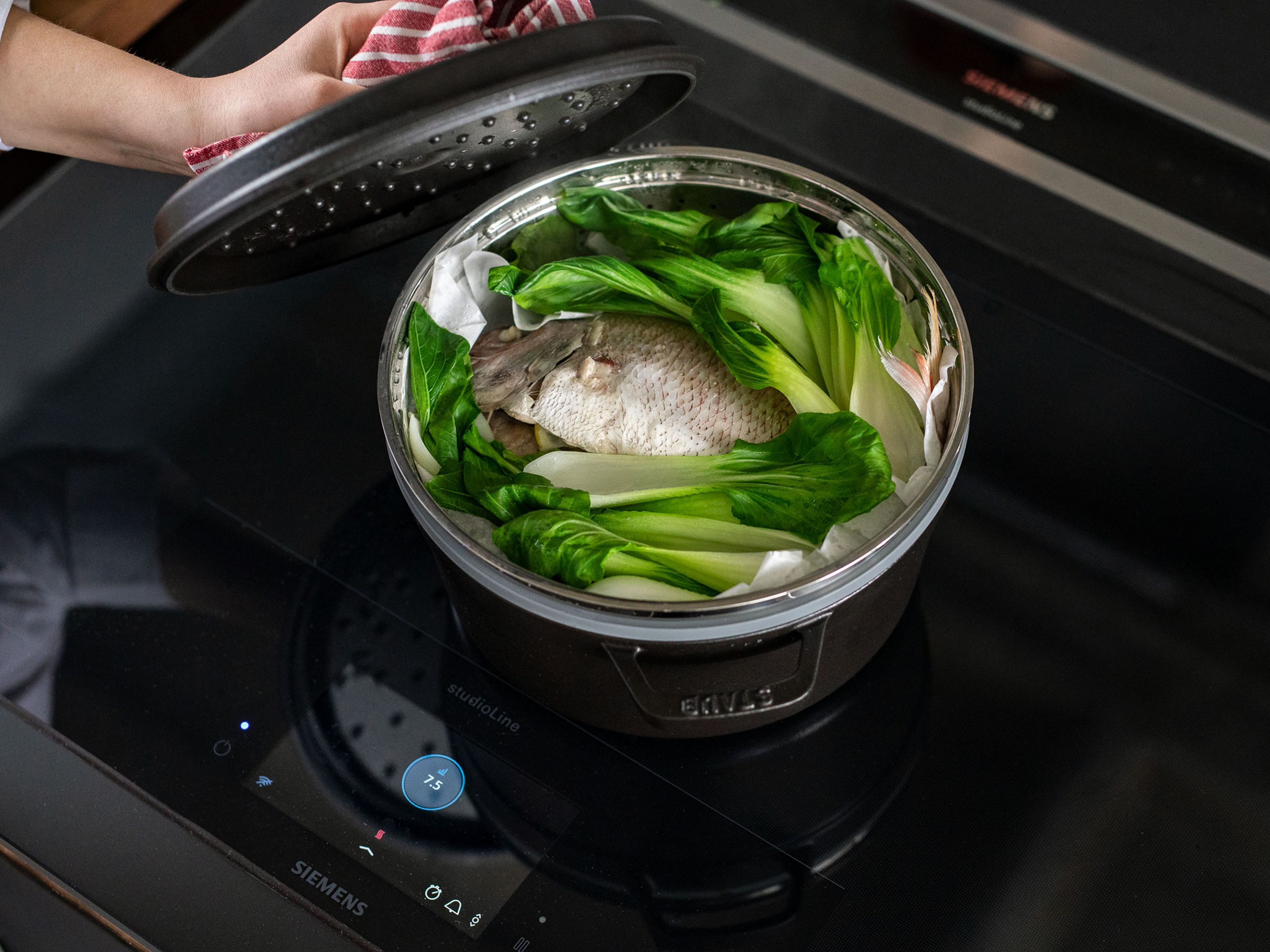 Line a steamer basket with baking paper. Put the fish in the steamer basket, set over the boiling water to steam. After approx. 5 min, add bok choy leaves to the basket, let steam for approx. 5 min more.