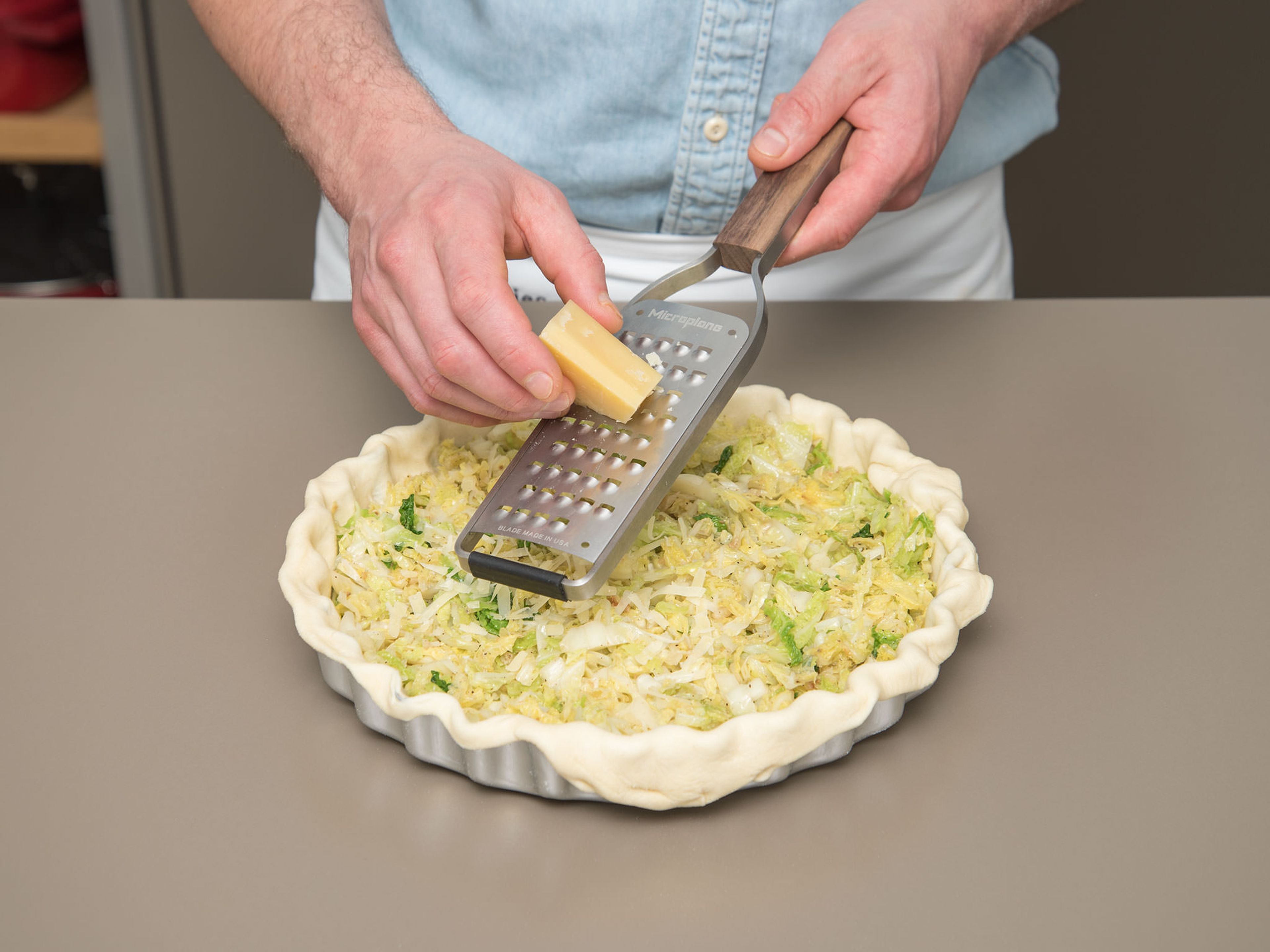 Thinly slice 2/3 of the Alpine cheese. Layer the bottom of the pan with cheese slices. Spread the cabbage over the dough so that it forms a small mound in the middle. Grate the rest of the cheese onto the cabbage.