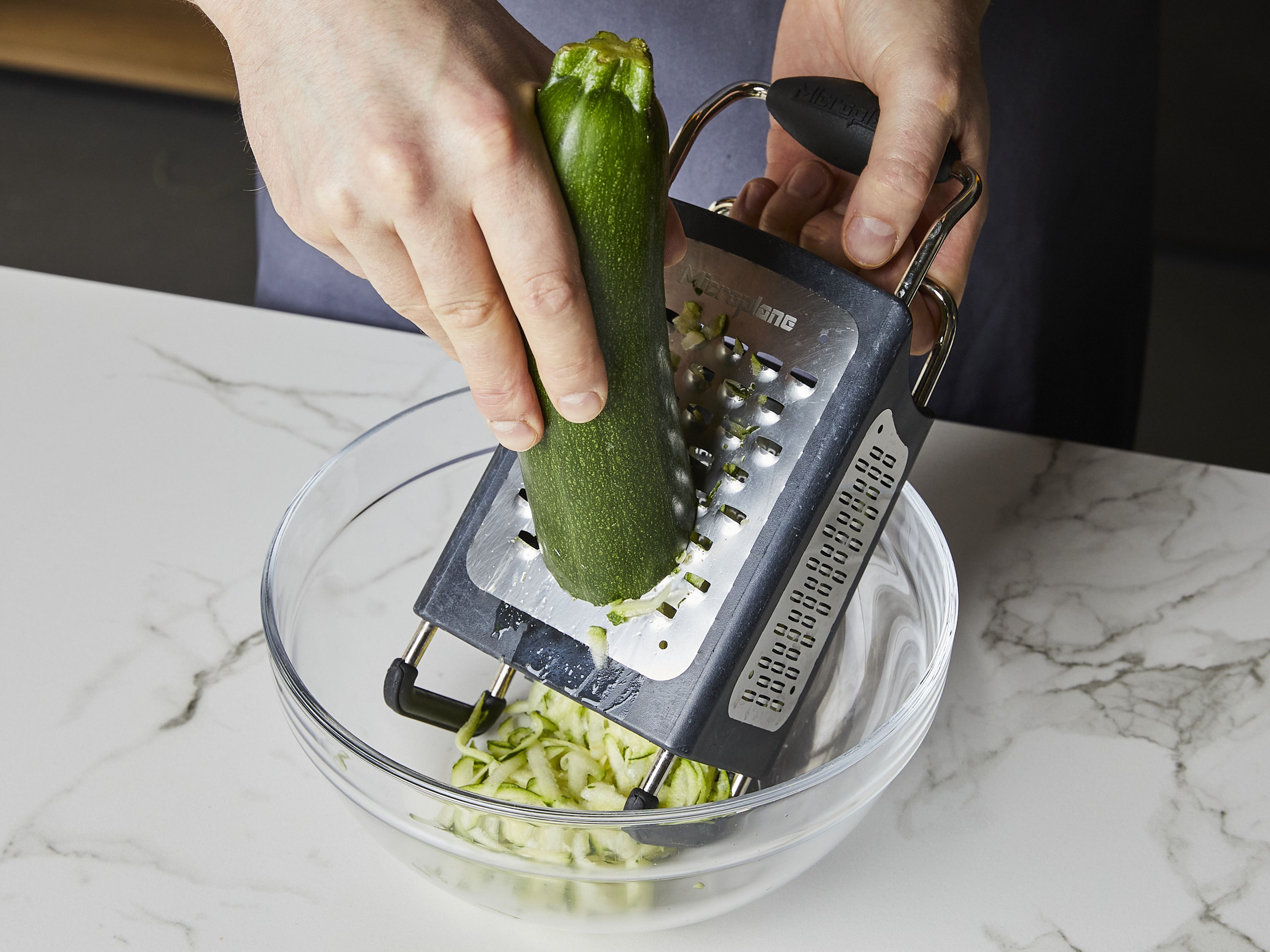 Zucchini grob in eine große Schüssel raspeln und großzügig mit Salz würzen. Beiseitestellen.