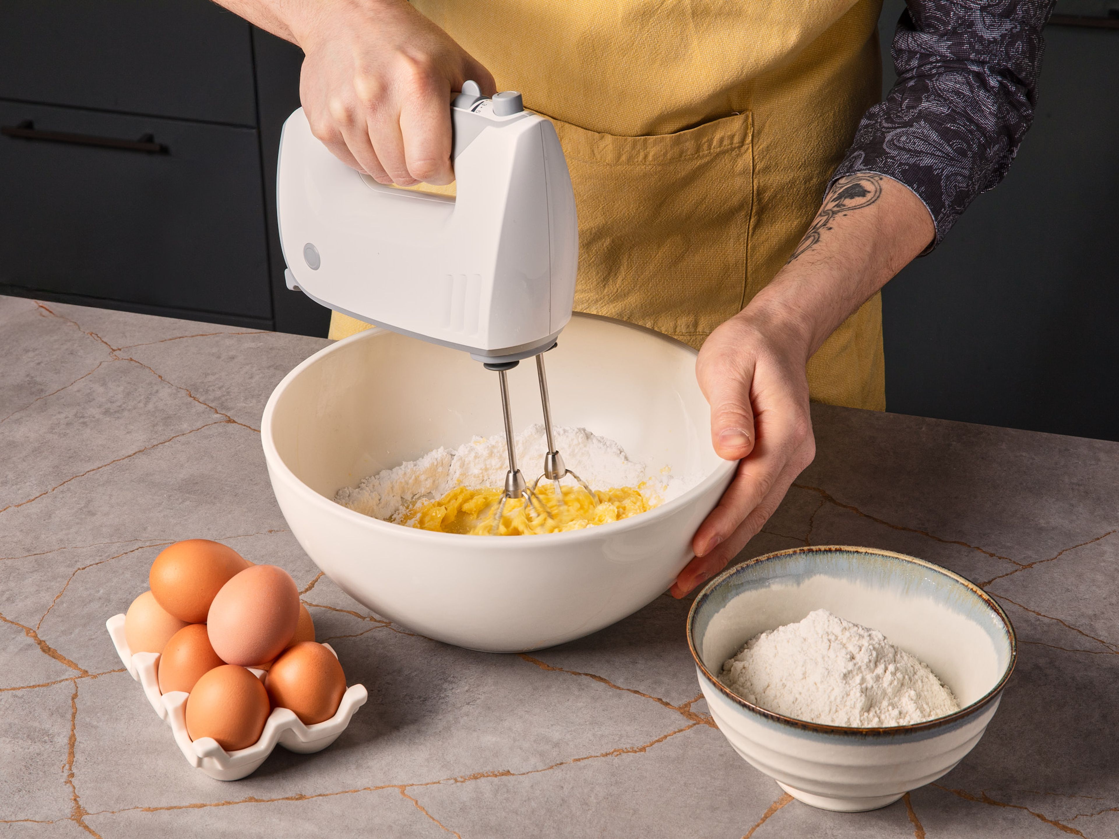 für den Marmorkuchen den Backofen auf 180°C vorheizen. Eigelb vom Eiweiß trennen. Eiweiß mit Zucker in einer Rührschüssel ca. 3–5 Min. steif schlagen. In einer separaten Schüssel Butter, Eigelb und Puderzucker ebenfalls ca. 3–5 Min. cremig aufschlagen.