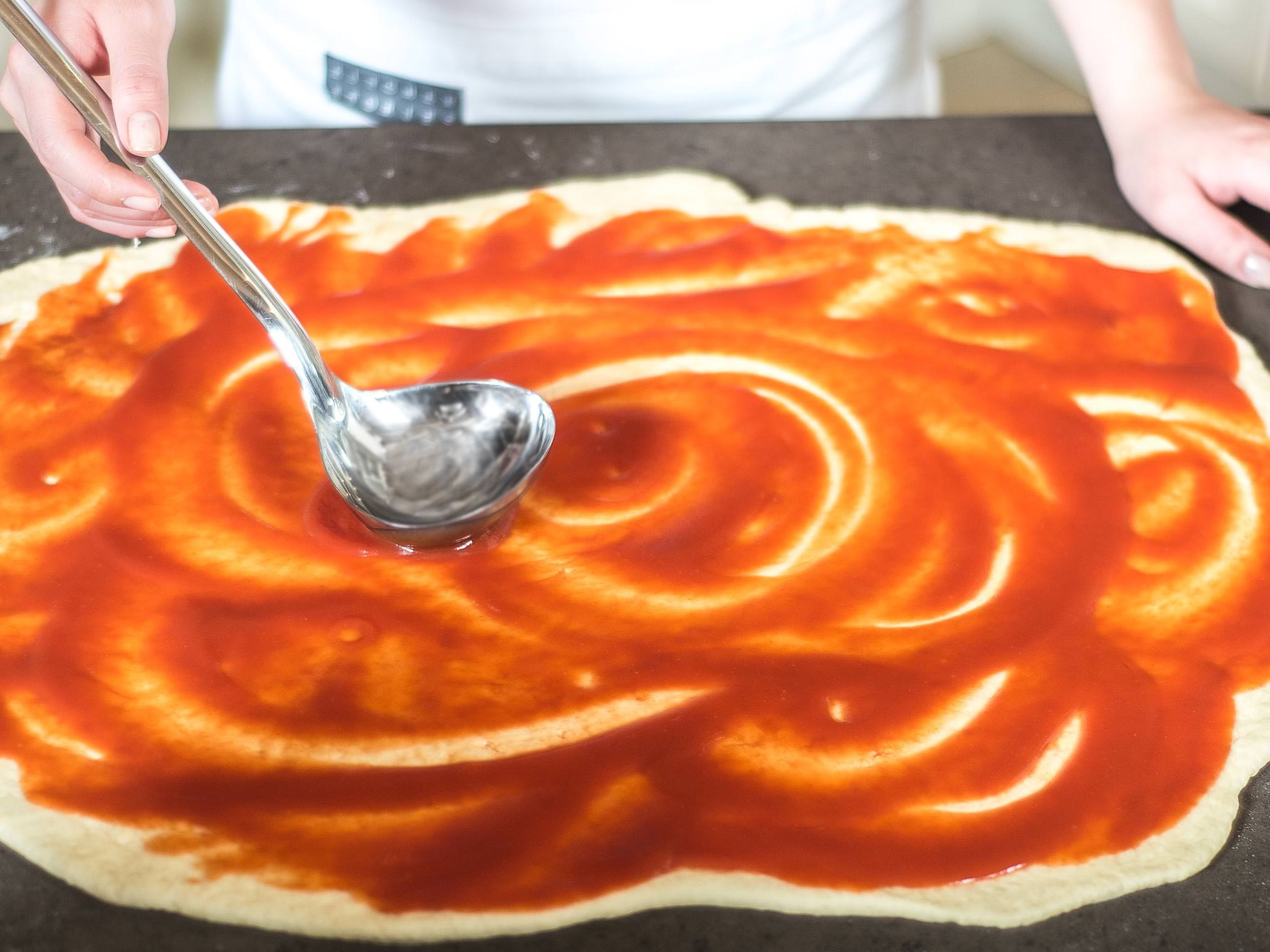 Roll the dough out flat onto a floured work surface and spread with crushed tomatoes.