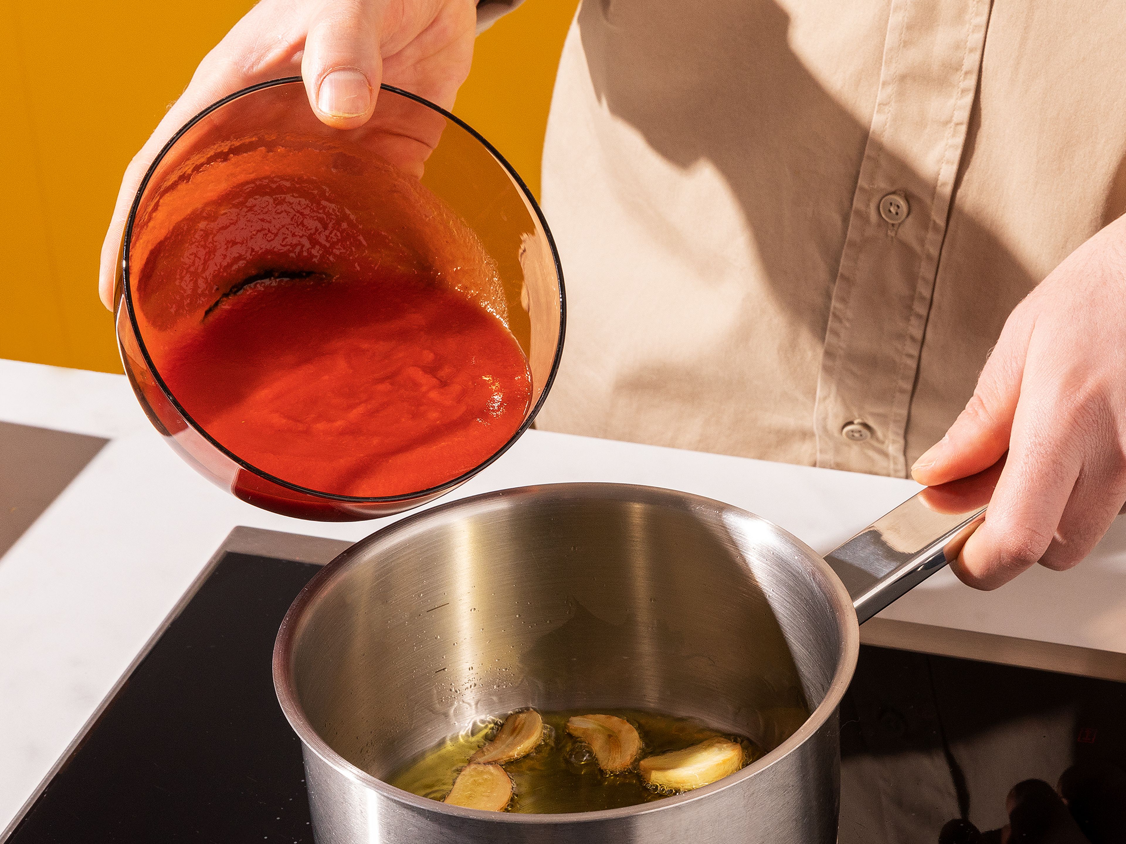 Inzwischen die Soße vorbereiten: Rest des Olivenöls mit dem Knoblauch in einen kleinen Topf geben und bei mittlerer Stufe solange erhitzen, bis der Knoblauch beginnt, bräunlich zu werden. Dann die passierten Tomaten hinzugeben und mit getrocknetem Oregano, Salz und Pfeffer würzen. Soße auf niedriger bis mittlerer Hitze köcheln lassen, bis das Ofengemüse fertig ist, ca. 5 Min.