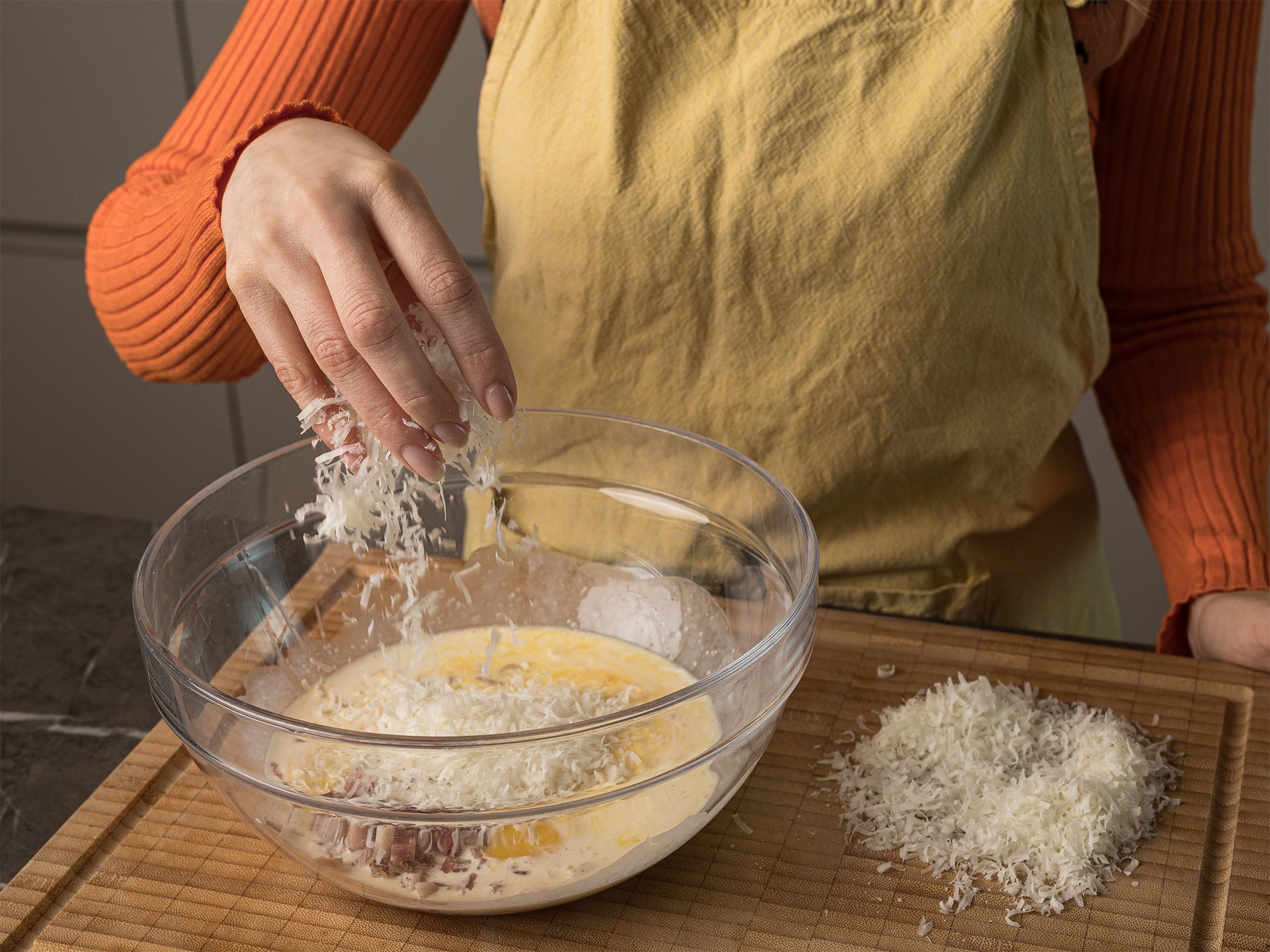 Knoblauchzehen schälen und mit dem Messerrücken zerdrücken. Parmesankäse fein reiben. In einer großen Schüssel die Eier aufschlagen und verquirlen, dann die Sahne, den geriebenen Mozzarella, den Parmesan und den Speck unterrühren. Mit Salz, Pfeffer und Muskatnuss würzen. Die gekochten Spaghetti dazugeben und alles gründlich vermischen.