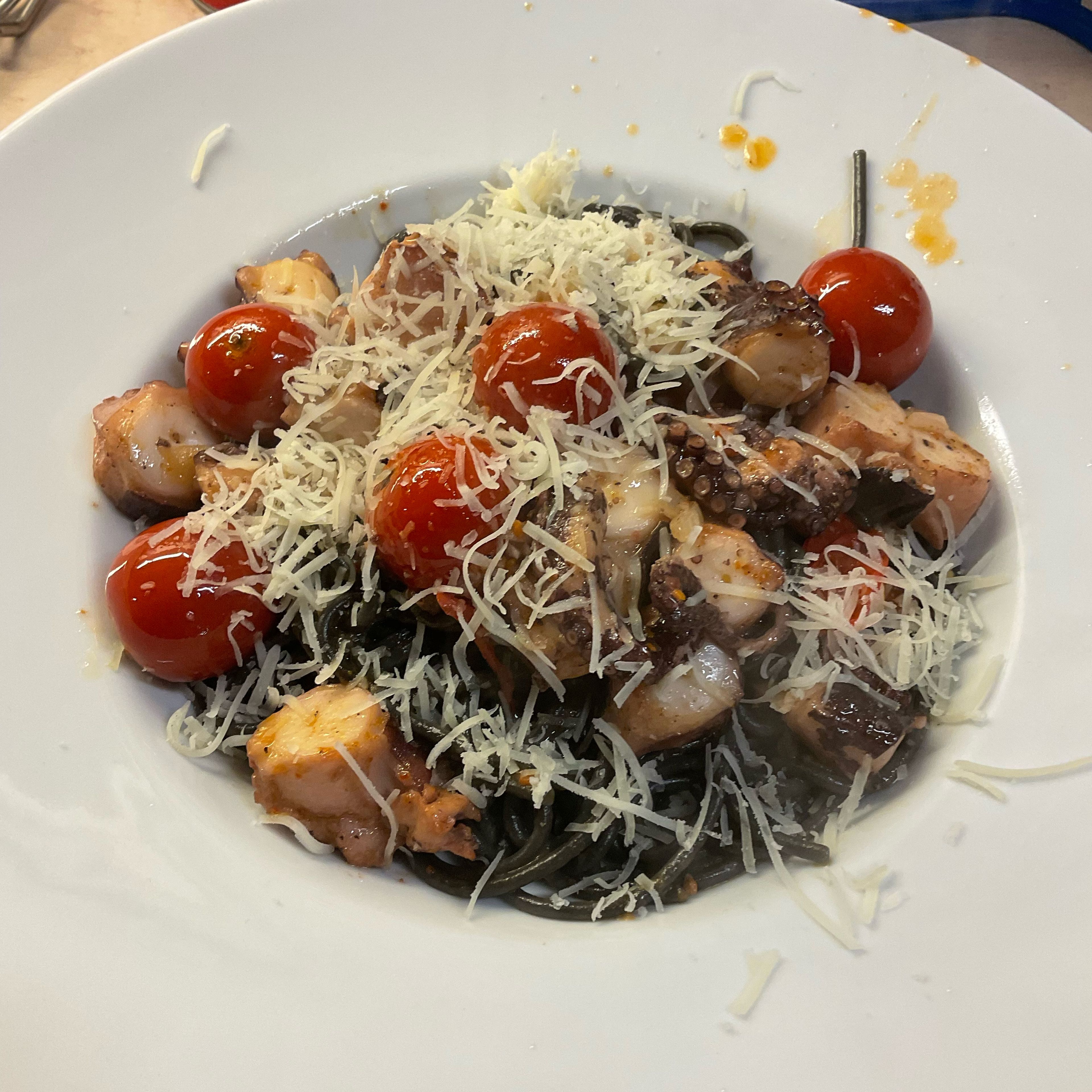 Spagetti negro mit der Spaghettikralle im tiefen Teller portionieren, die superheißen Pulpo/Kirschtomaten drüber drapieren und den Pecorino drauf streuen.