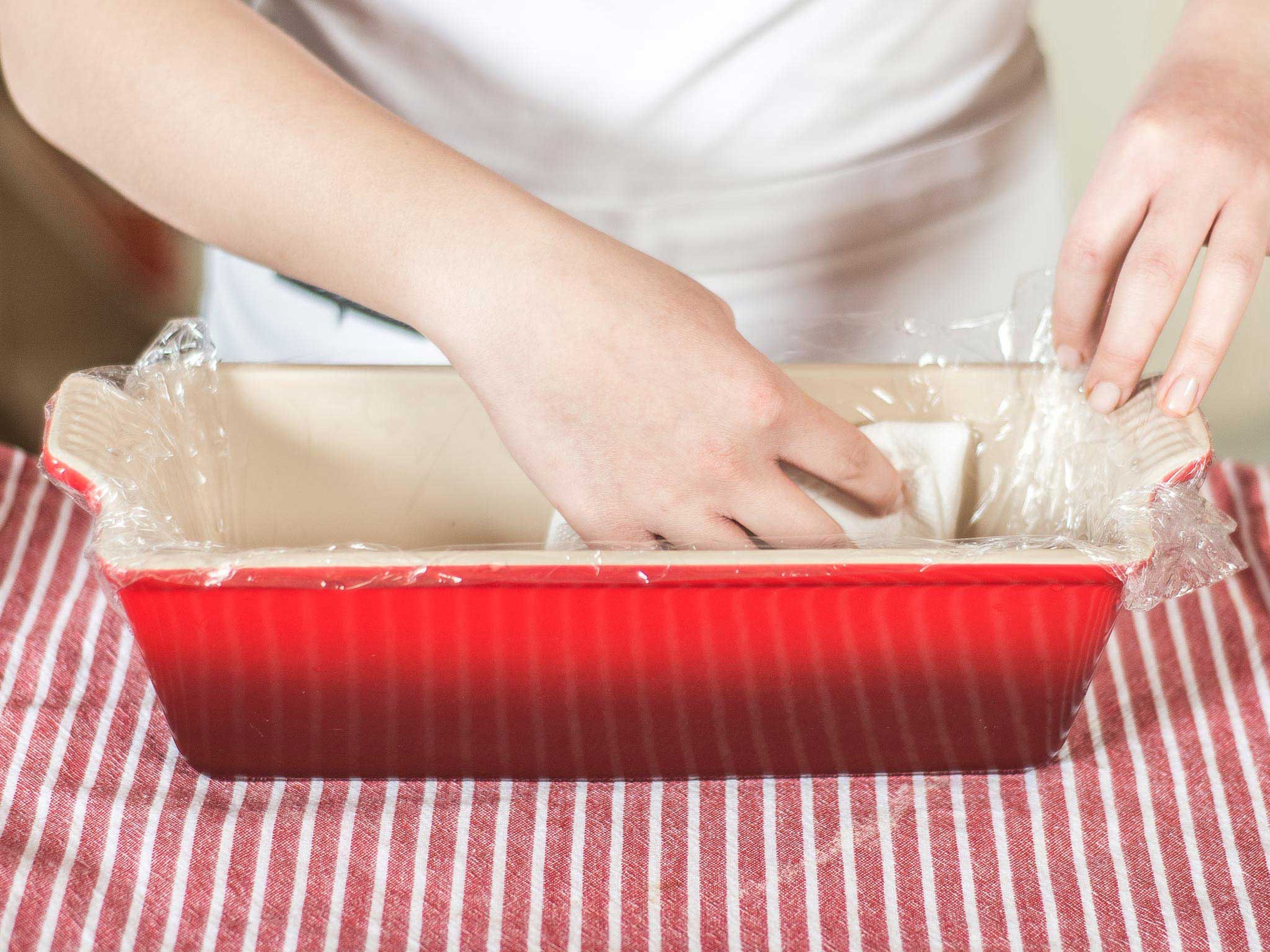 Line the terrine form with plastic wrap. This works best when the form is filled with a small amount of water, allowing the plastic wrap to lie perfectly inside it. Then pour out the water and pat dry.