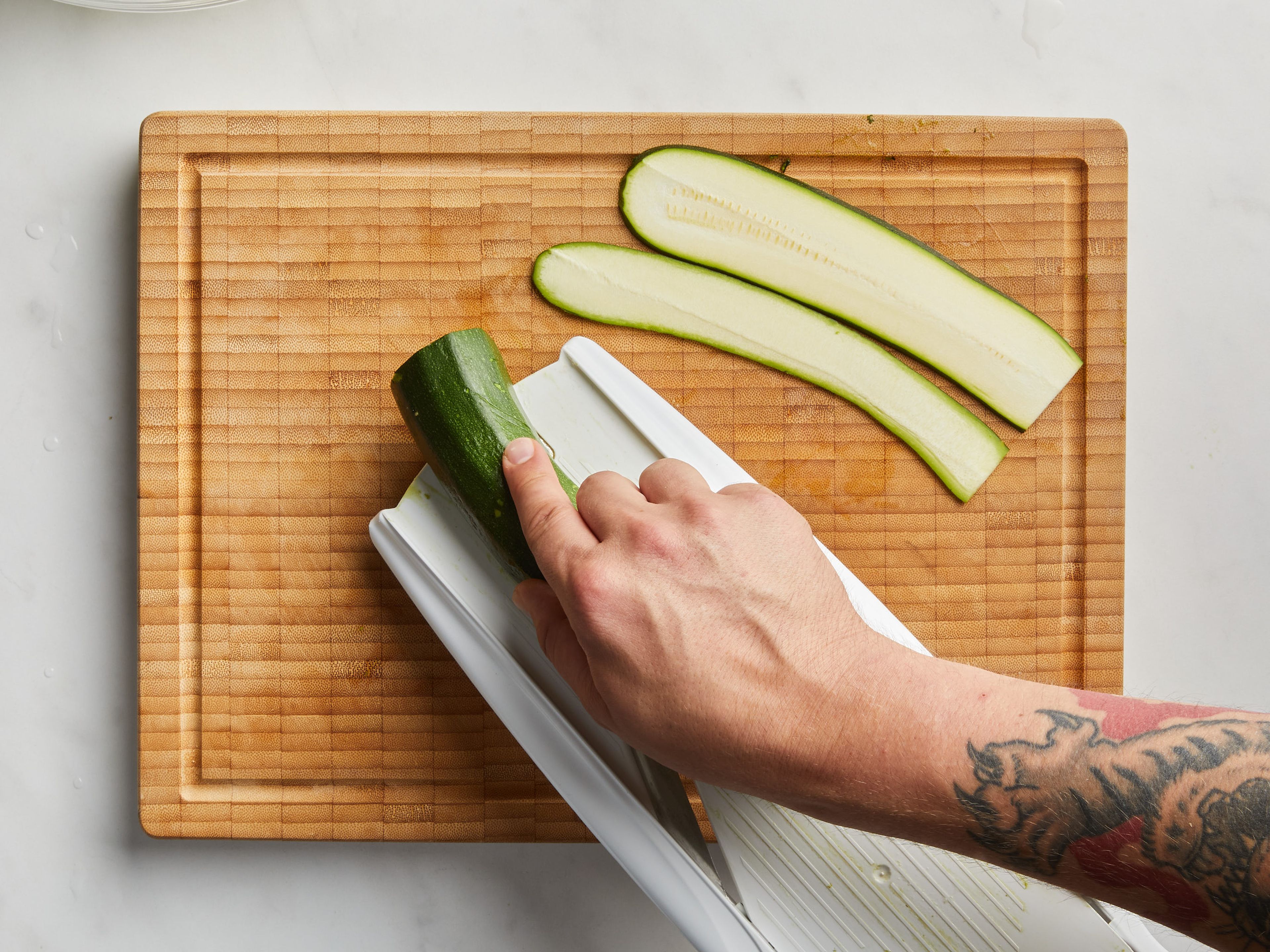 Preheat the grill, if using. Place skewers in hot water and soak for at least 10 min. In the meantime, slice the zucchini lengthwise with a knife, a mandoline or a wide peeler into slices about 3 mm / 0.1 in. thin. In a bowl, coat the zucchini slices with a little salt. Cut the halloumi into 24 equal-sized cubes. Each cube should be about 2.5 x 2.5 cm (1 x 1 in.). Slice the mint chiffonade, creating thin ribbons.