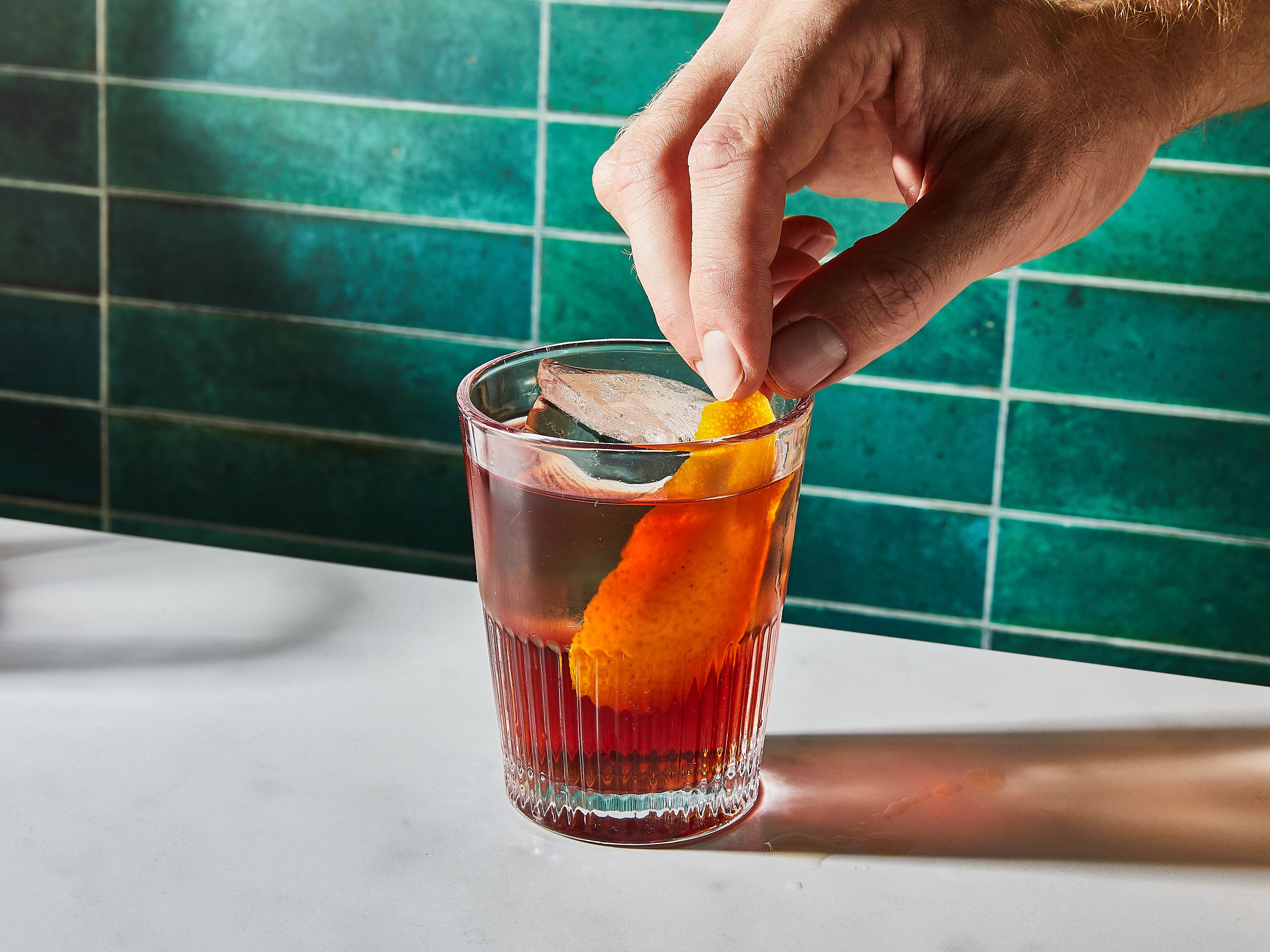 Cut a strip of orange peel, rub it around the rim of the glass, and then garnish your drink with it.