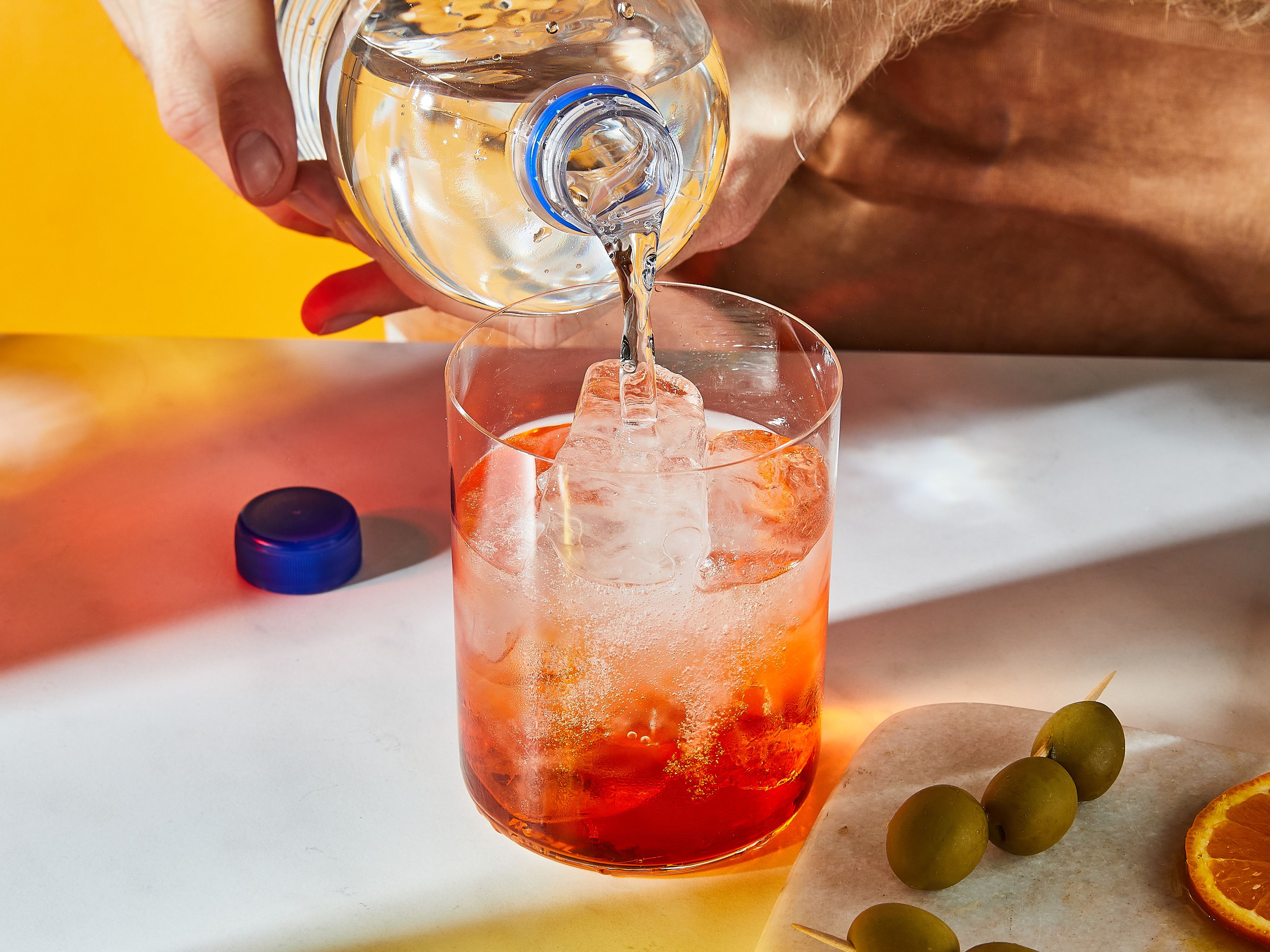 Eiswürfel in ein Weinglas geben. Aperol und Prosecco hinzugeben und mit Sodawasser auffüllen. Mit Orangenscheiben und Olivenspießchen garnieren.