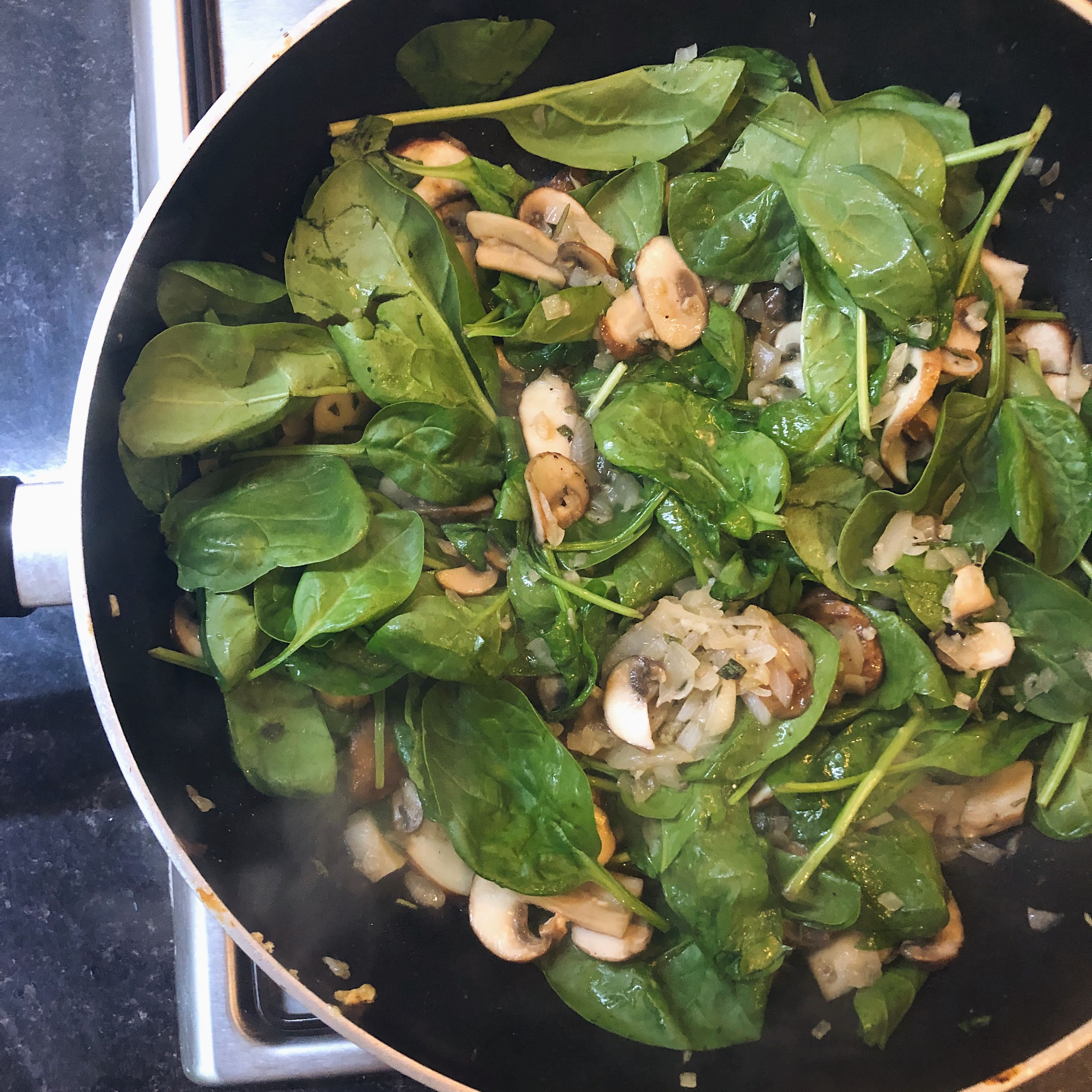 While onions are sweating, slice mushrooms. Then add mushrooms and spinach to the pan and cook for 10 minutes.