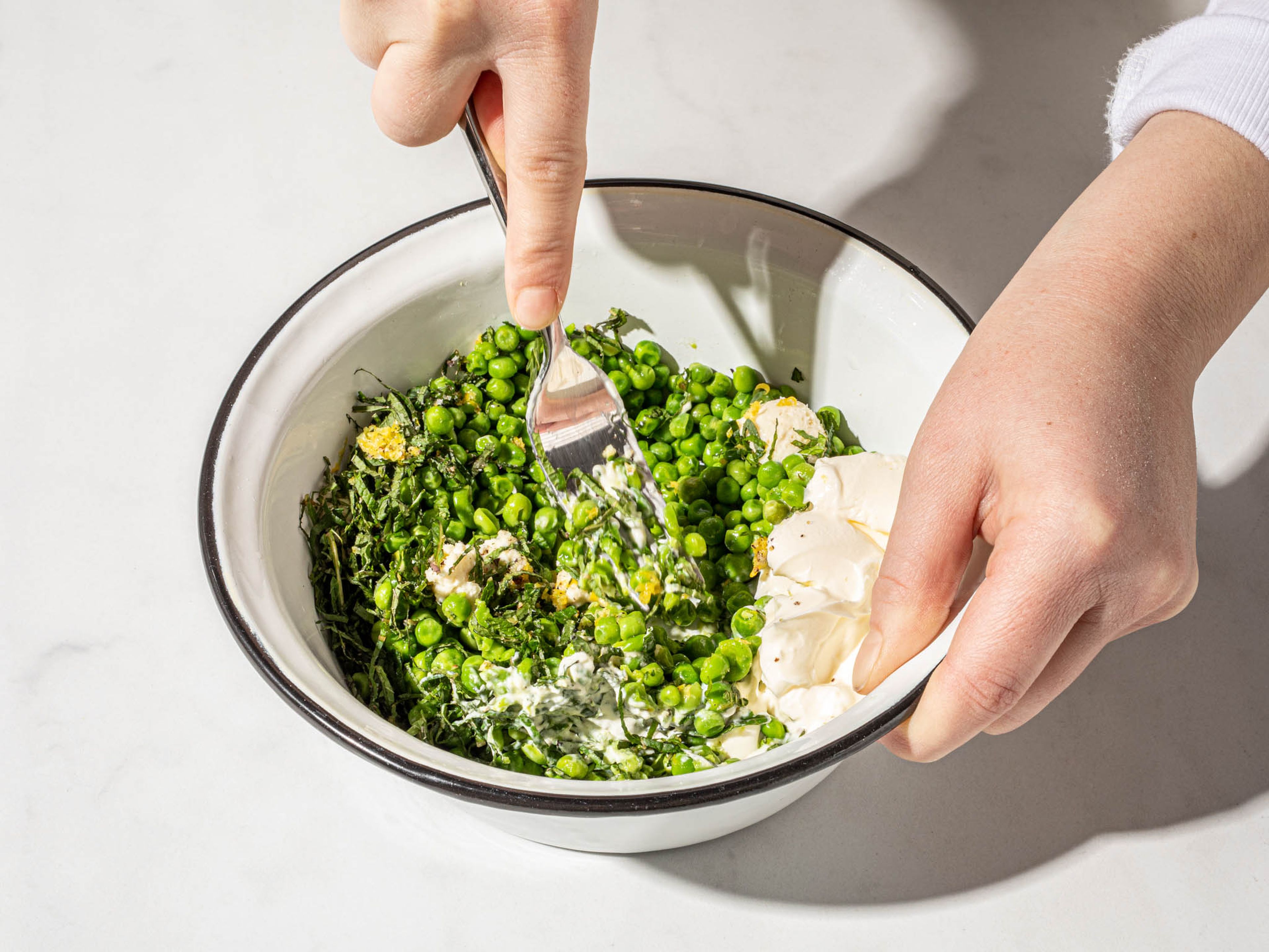 To a bowl add peas, some mint, crème fraîche, horseradish, zest and juice of half a lemon. Season with salt and pepper. Mash into a rough paste with a fork.