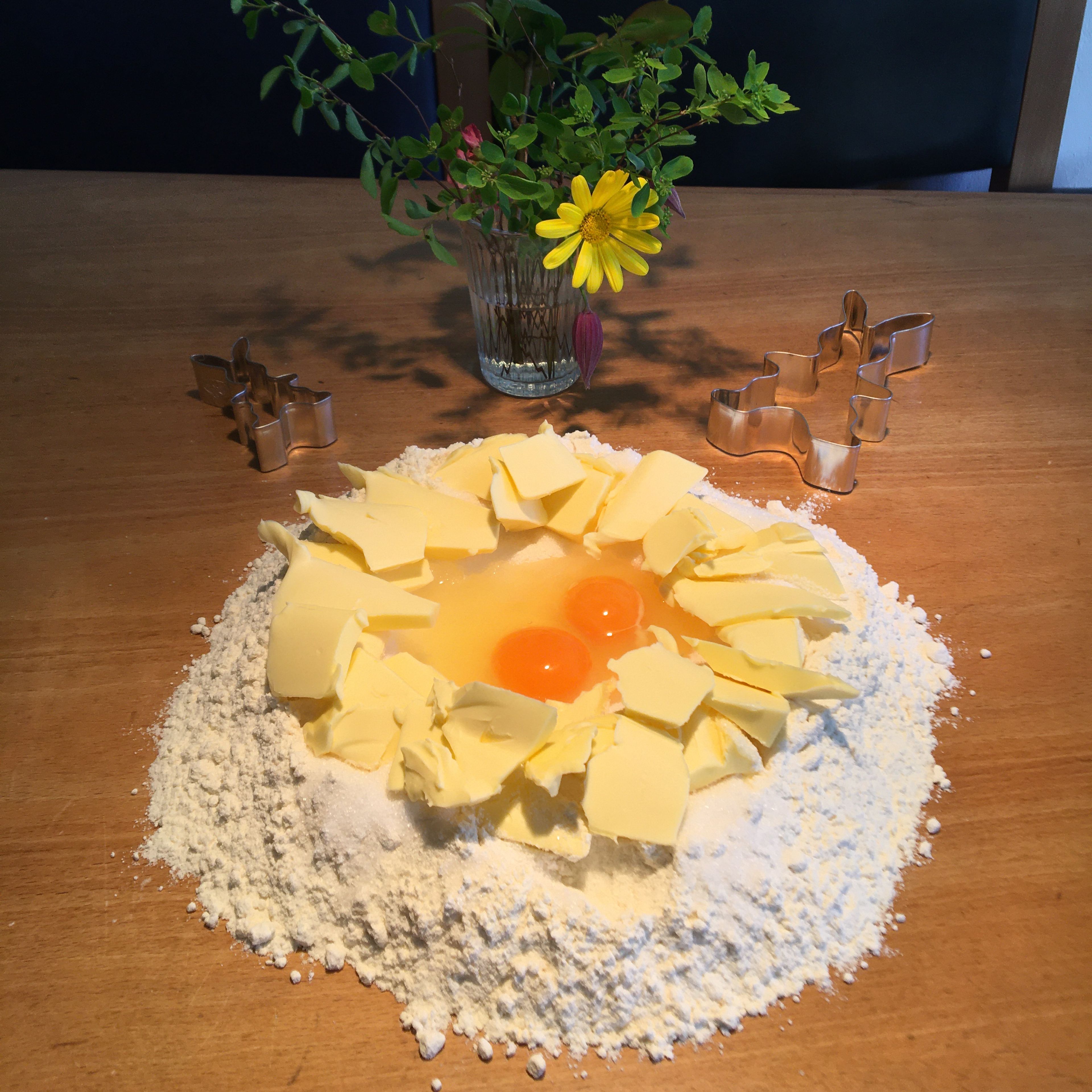 Das Mehl auf die Arbeitsfläche sieben. Mit der Hand eine große Mulde in den Mehlberg drücken und den Zucker hinein streuen. Das Ei aufschlagen und ebenfalls in die Mulde geben. Die Butter schneiden und rundherum auf den Mehlrand setzen.
