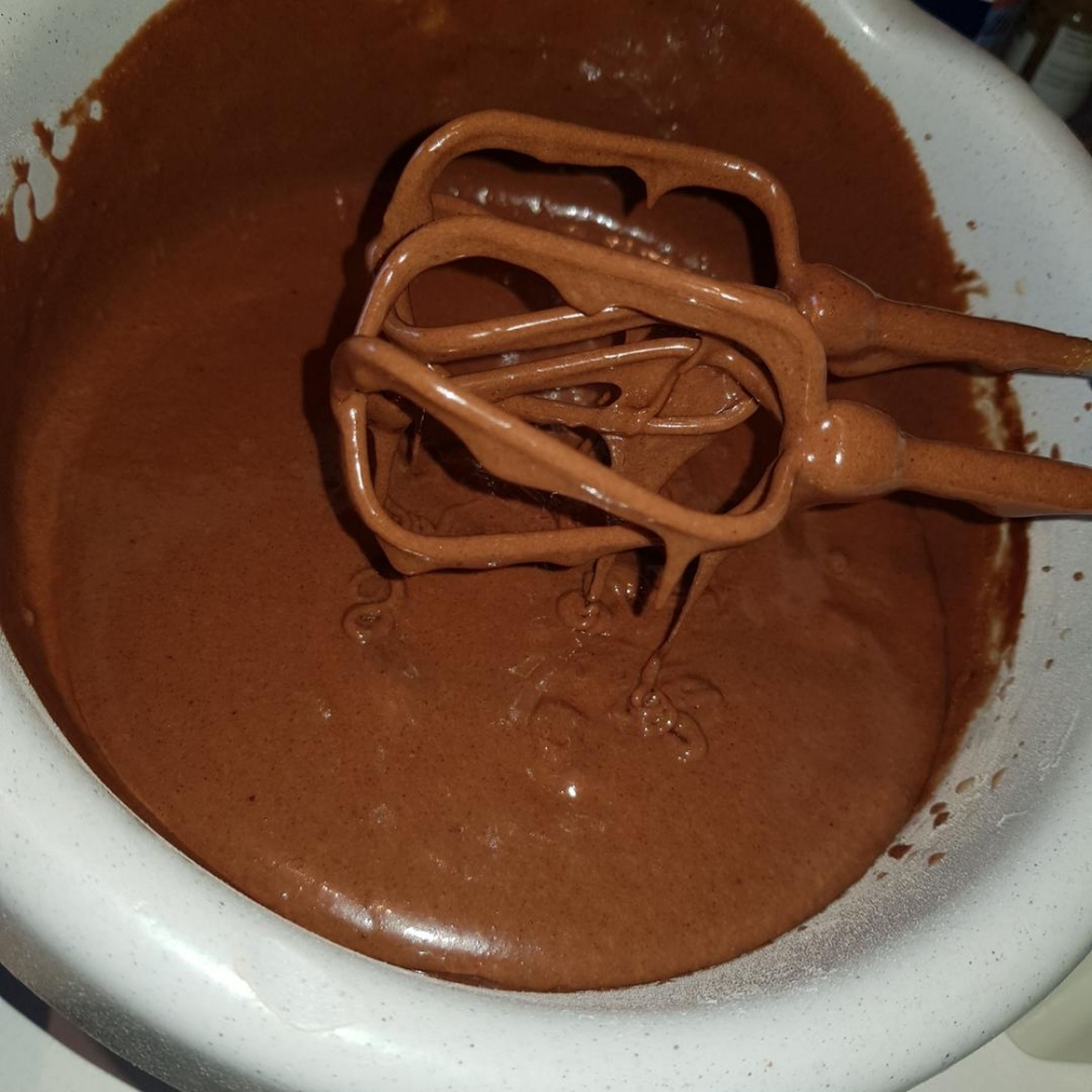 Die Schokoladenmischung mit Raumtemperatur in drei Etappen hinzugeben und unterrühren, bis ein glatter Teig entstanden ist.