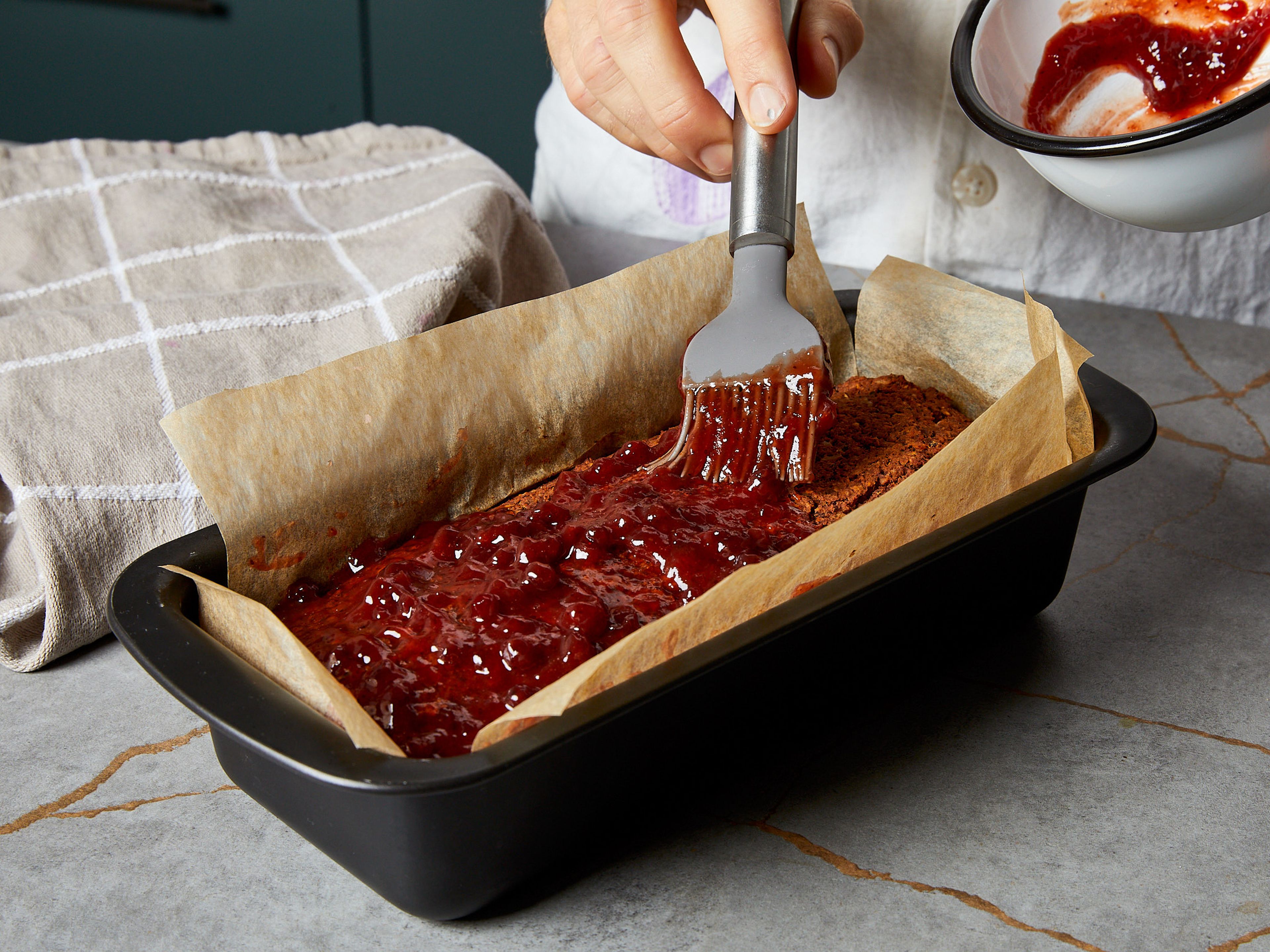 Mixe in der Zwischenzeit Preiselbeeren und Ketchup für die Glasur in einer kleinen Schüssel zusammen. Streiche die Glasur nach 25 min. Backzeit auf den veganen Braten und backe ihn für weitere 15 min. im Ofen. Den veganen Braten mindestens 15 min. abkühlen lassen, damit sich die Masse setzen kann und alles gut zusammenhält. Mit veganer Bratensauce, Röstkartoffeln und Rotkraut servieren.