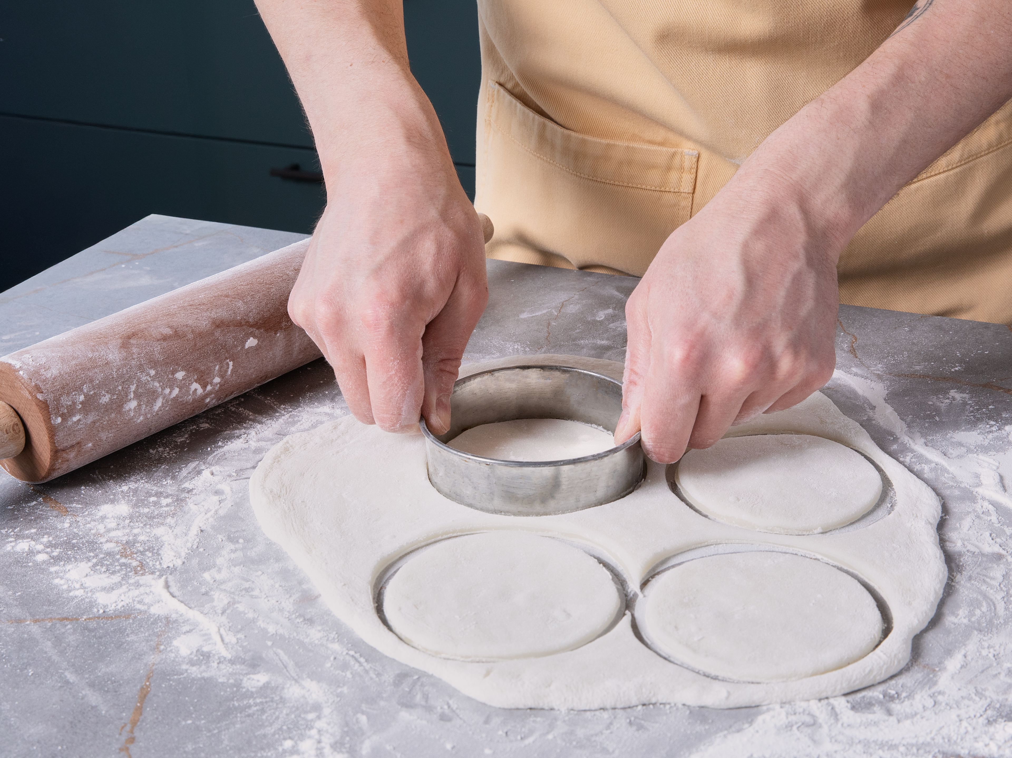 Eine saubere Arbeitsfläche großzügig mit Stärke bestäuben. Den fertigen Mochi-Teig darauf geben, ebenfalls mit Stärke bestäuben und mit einem Nudelholz ca. 5 mm dick ausrollen. Mit einem Ausstecher Kreise ausstechen (ca. 10 cm Ø). Alternativ den Teig mit einem Messer in Quadrate schneiden. Anschließend abkühlen lassen.
