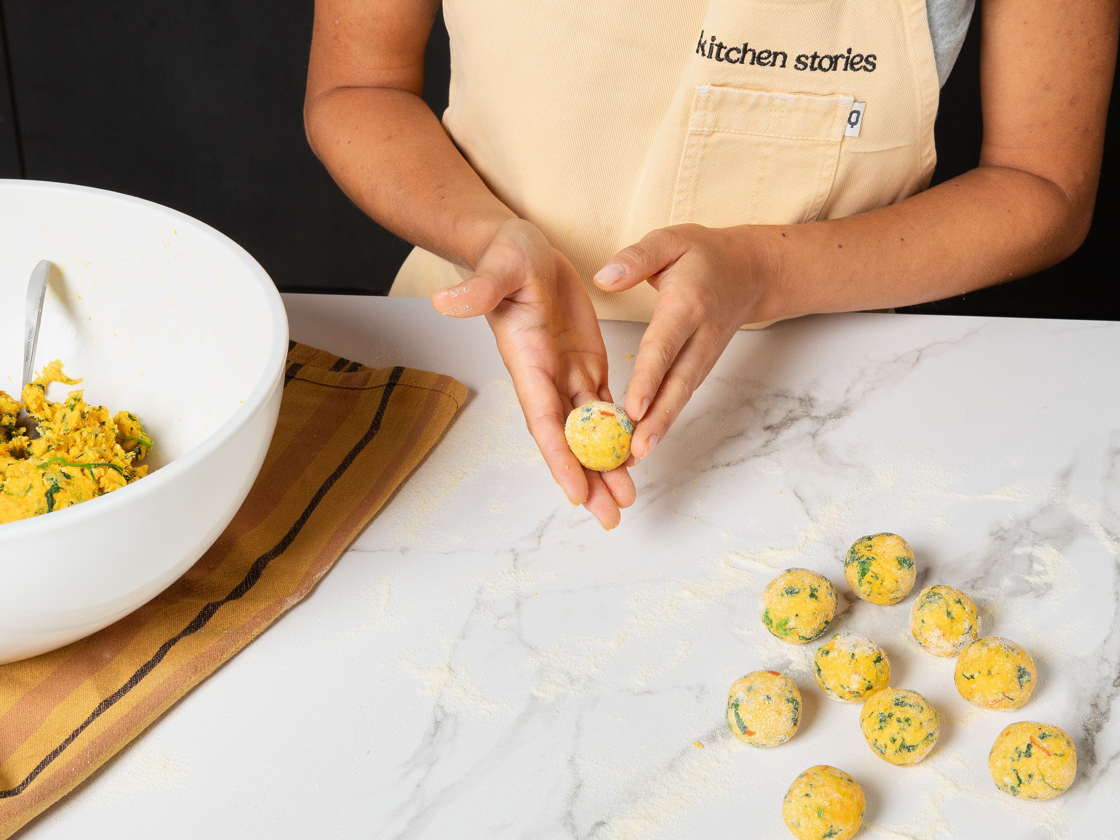 Etwas mehr Hartweizengrieß auf der Arbeitsfläche verteilen. Die Gnudi mit einem Teelöffel portionieren und im Hartweizengrieß zu Kugeln formen. Die geformten Gnudi ca. 30 Min. ruhen lassen.