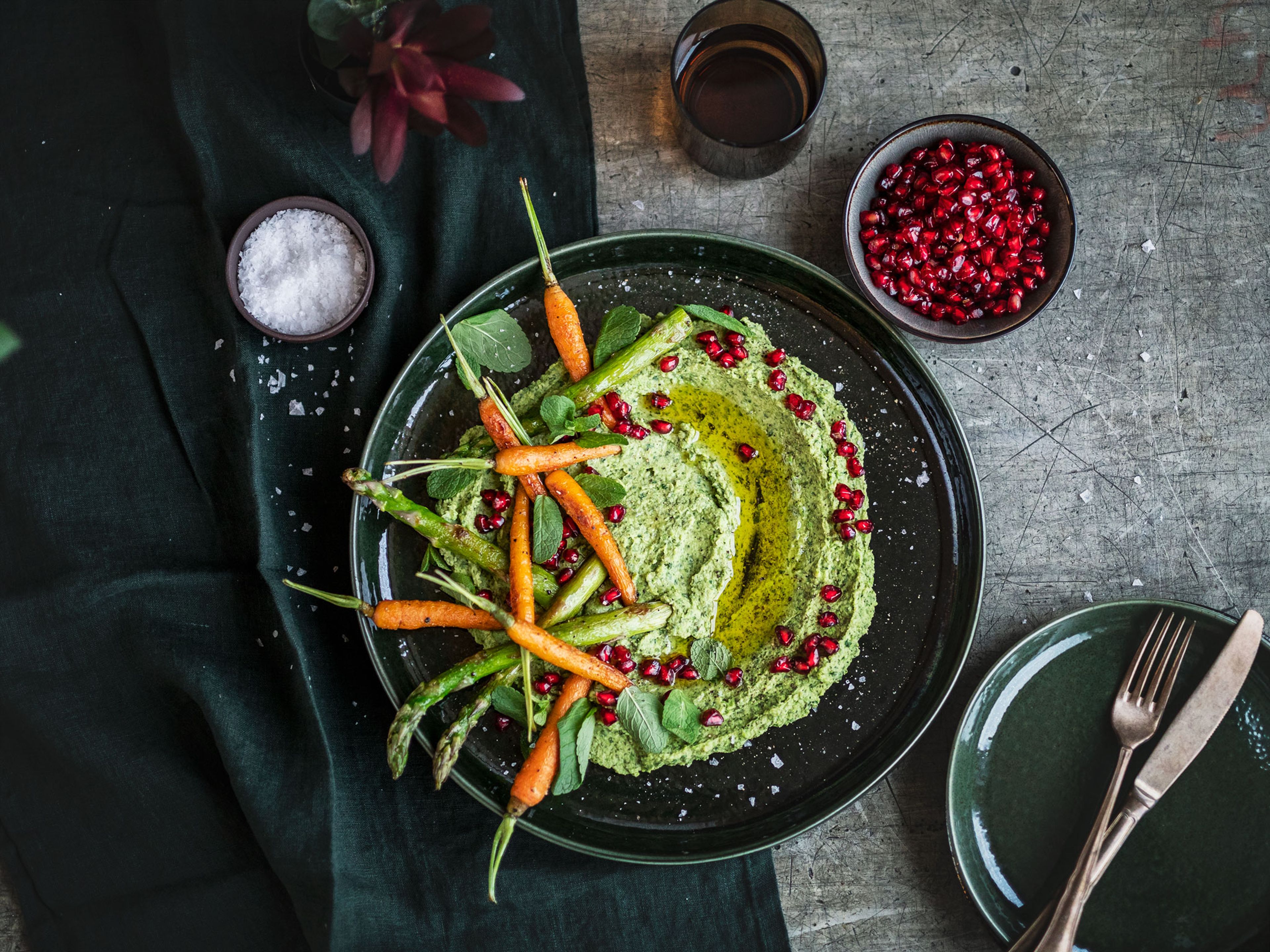 Add hummus to a serving plate, top with the charred carrots and asparagus, and garnish with pomegranate seeds and a drizzle of olive oil. Enjoy!