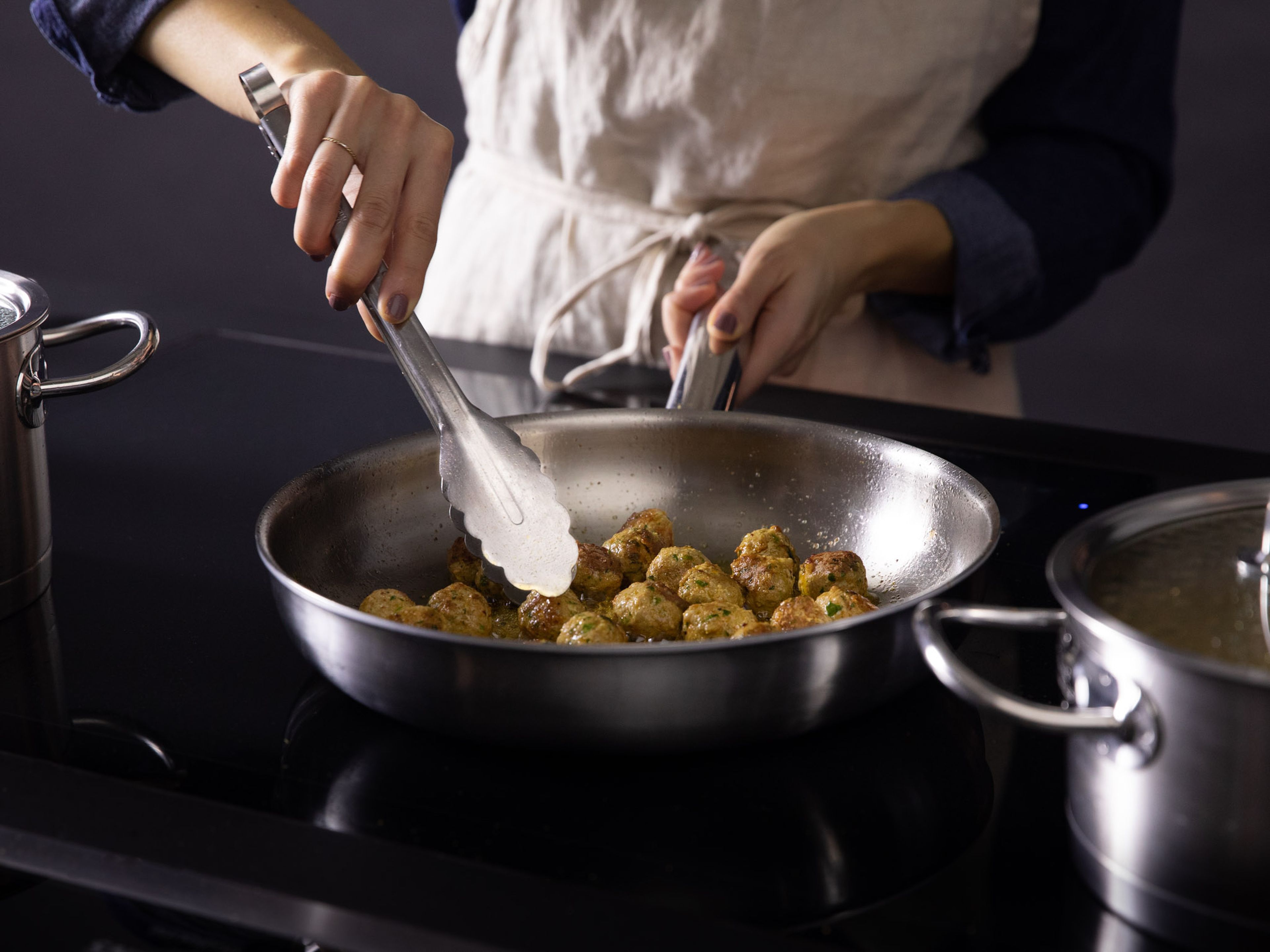 Bring a small pot of water to a simmer. Use tongs to add the meatballs one at a time and let cook just until they hold their shape and no pink shows, approx. 5 min. In a frying pan over medium heat, add some oil and fry the meatballs until brown on all sides, approx. 8 min. Remove and set aside.