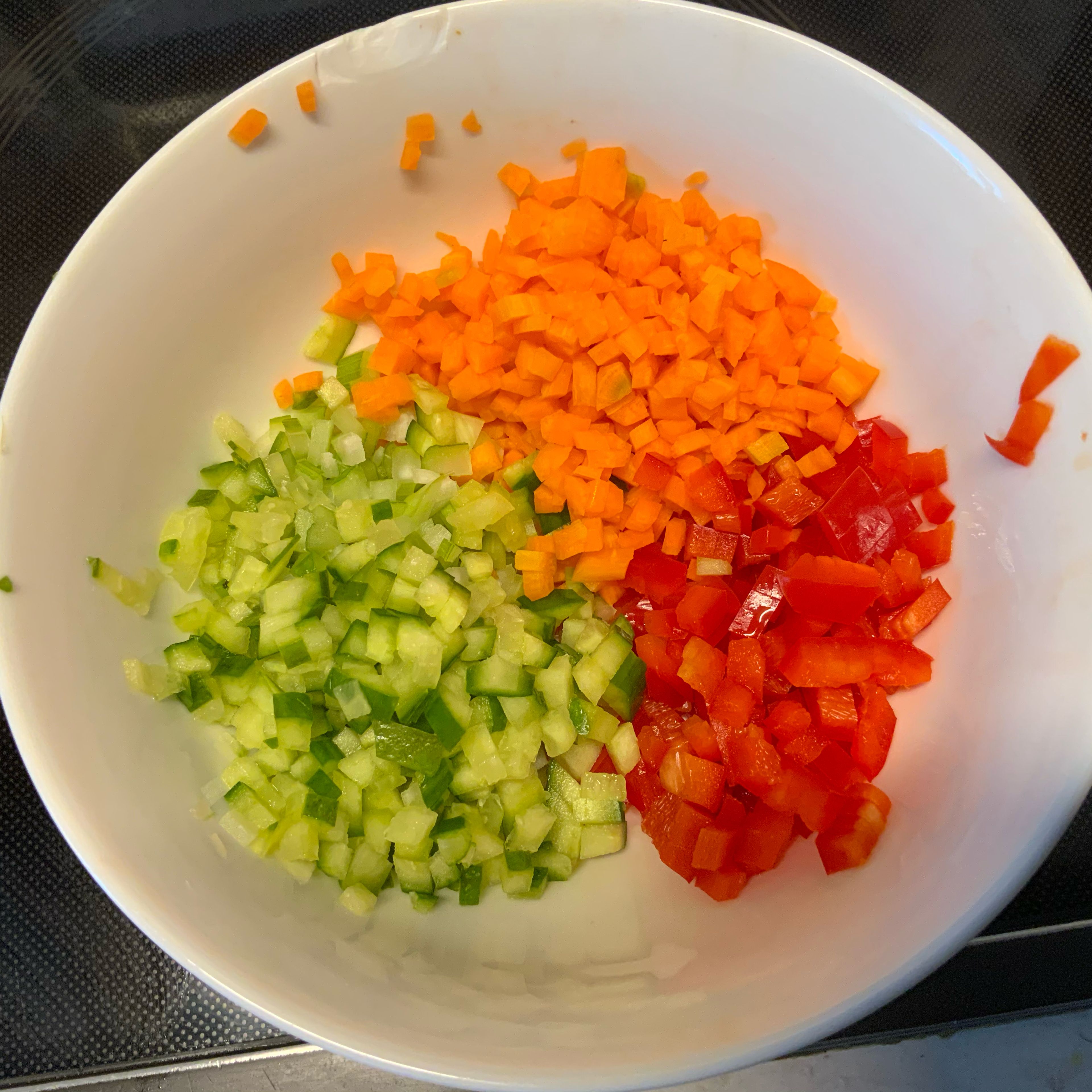 Das Gemüse-Couscous kann man entweder so zubereiten, dass man entweder das Couscous mit kochendem Wasser übergießt, ihn ca.10 Minuten quellen lässt und dann die 1/4 Karotte, den Teil roten Paprika und die viertel Stange Staudensellerie in den gequollenen Couscous rein raspelt oder vorher -wie hier- in klitzekleine Würfelchen schneidet und hinzufügt. Je nach Geschmack kann man diese Microwürfelchen ganz kurz andünsten oder wer’s wie ich knackig mag roh in den gequollenen Couscous untermischen.