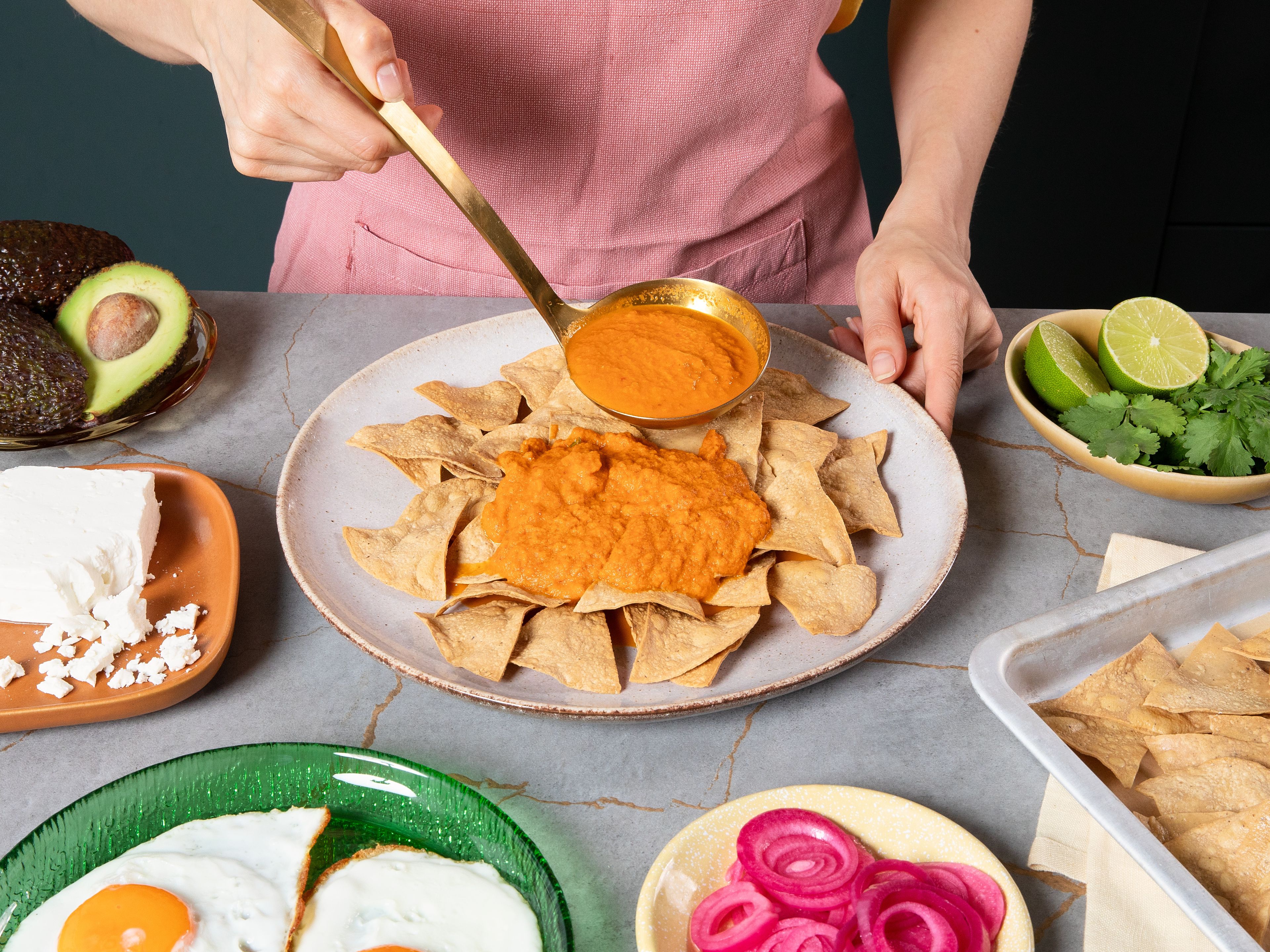 Return salsa to the previously used pan and heat again. Divide tortillas between plates and top with the hot salsa. Finish with the fried eggs, avocado, crumbled feta, pickled red onions, and cilantro leaves, and serve with lime wedges.