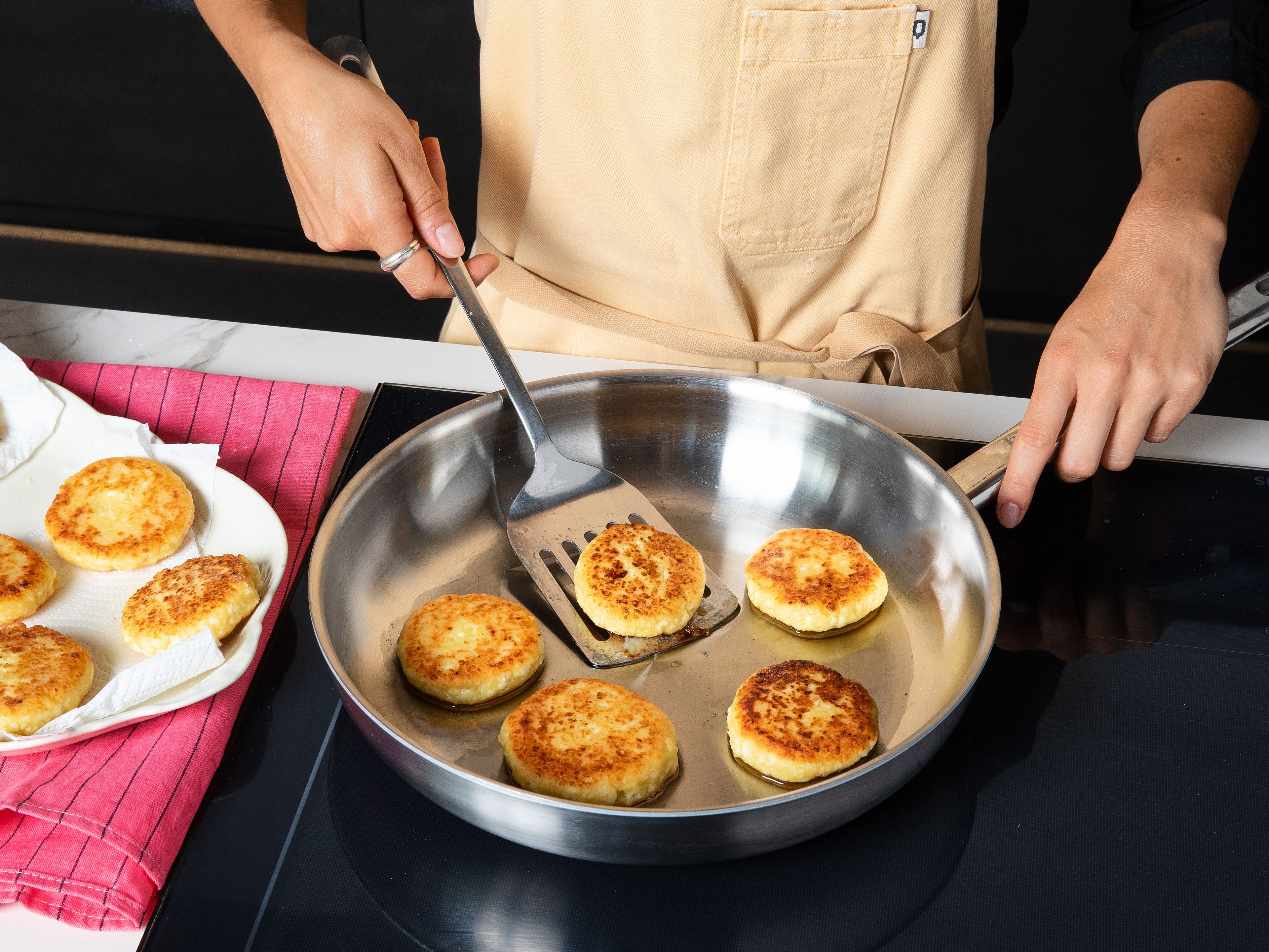 Add the remaining flour on a plate. Coat each syrnik in the flour and gently shake off any excess. Heat vegetable oil in a pan and fry the syrniki over medium heat for approx. 4–5 min. per side, until golden brown. Transfer to paper towels to drain.