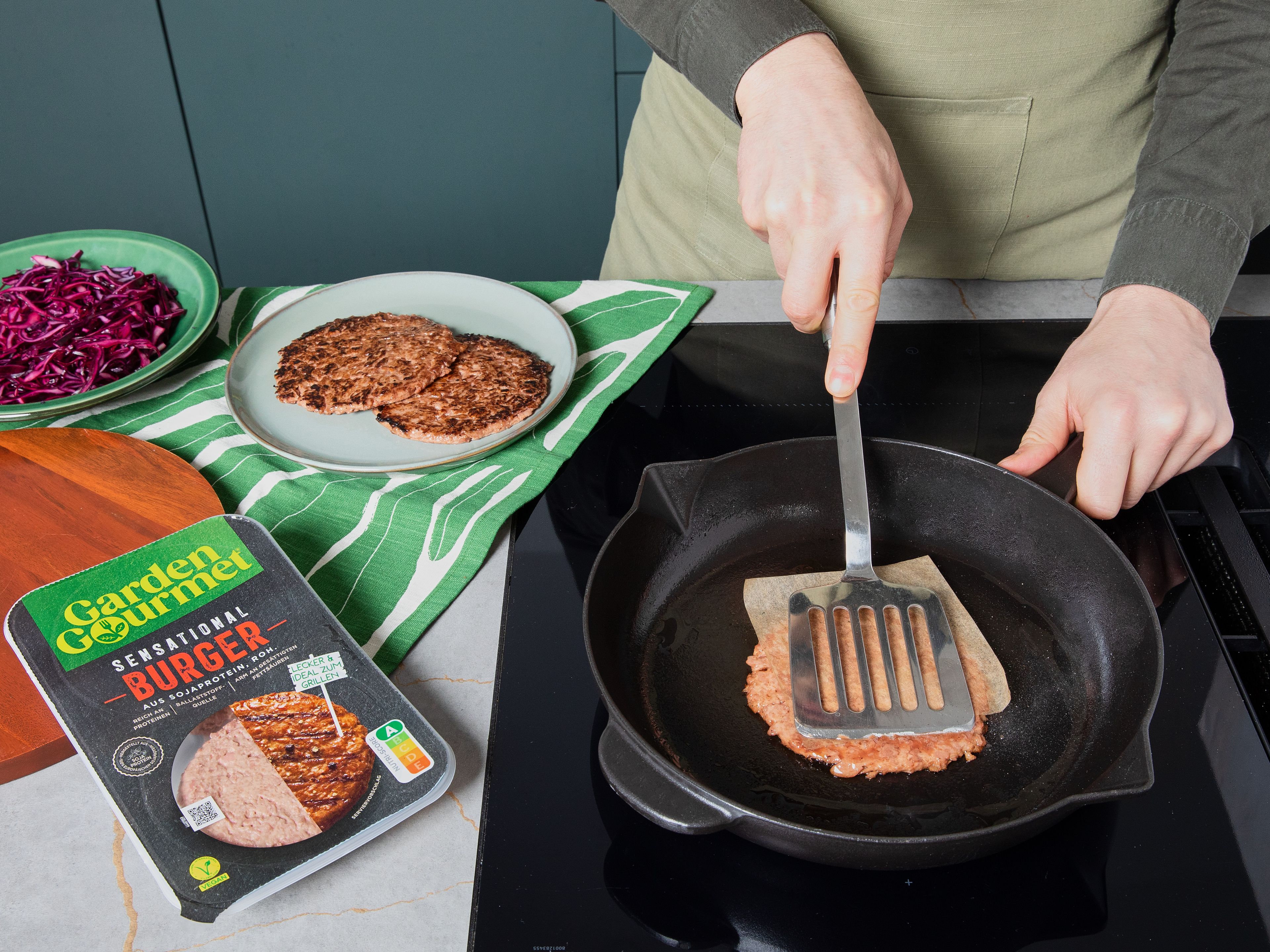 Eine Pfanne ohne Fett erhitzen, Reis-Buns halbieren und die Schnittflächen goldbraun anrösten. Anschließend Öl in derselben Pfanne erhitzen, die Garden Gourmet Sensational Burger hineingeben und mit einem flachen Küchenspachtel kräftig flach drücken. Tipp: Ein kleiner Topfboden mit Backpapier geht genauso gut. Die Patties bei hoher Hitze knusprig braten, wenden, Pfanne vom Herd nehmen. Die Patties mit Teriyaki-Soße glasieren, bis sie glänzend überzogen sind und mit Frühlingszwiebeln und Sesam bestreuen.