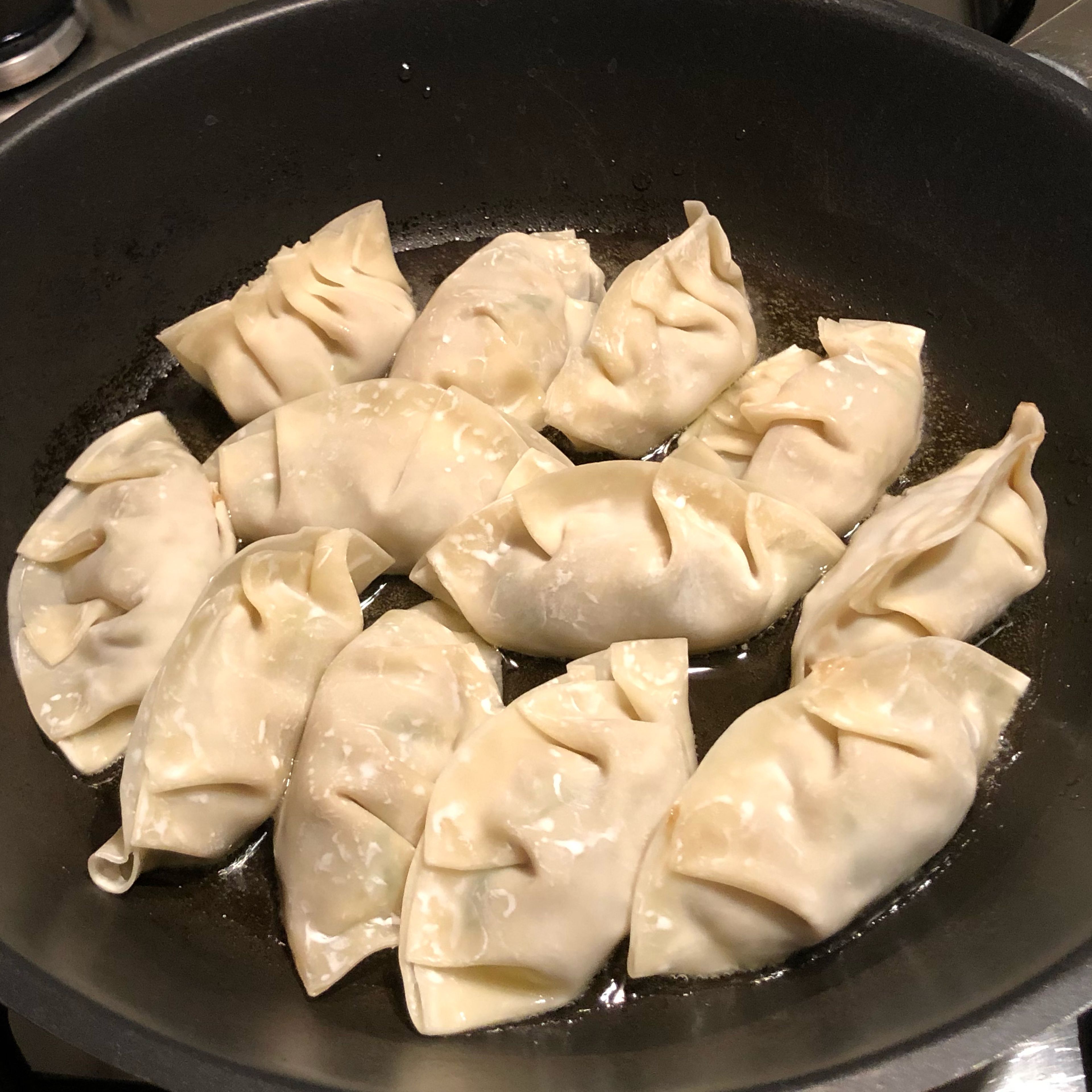 The gyoza are first fried on their flat side until the bottom is nice and brown. Then, water is added and the pan sealed with a lid until the upper part of the gyoza is steamed. You know the gyoza is done when all the water is gone.