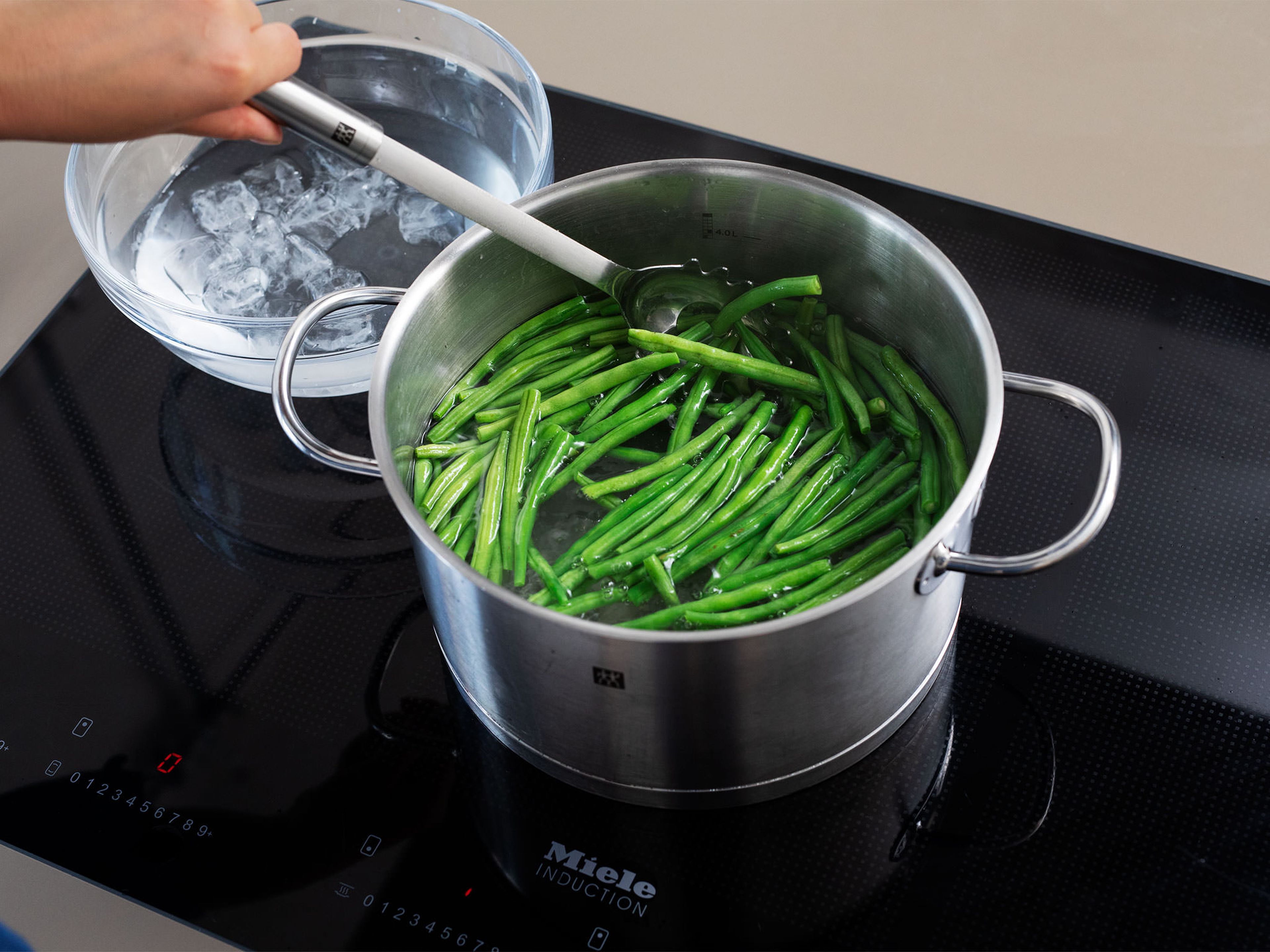 Trim green beans. Boil a large pot of water with plenty of salt. Blanch green beans for approx. 2 min., then transfer to a bowl of ice water to stop the cooking process. Remove from water, transfer to another bowl, and set aside.
