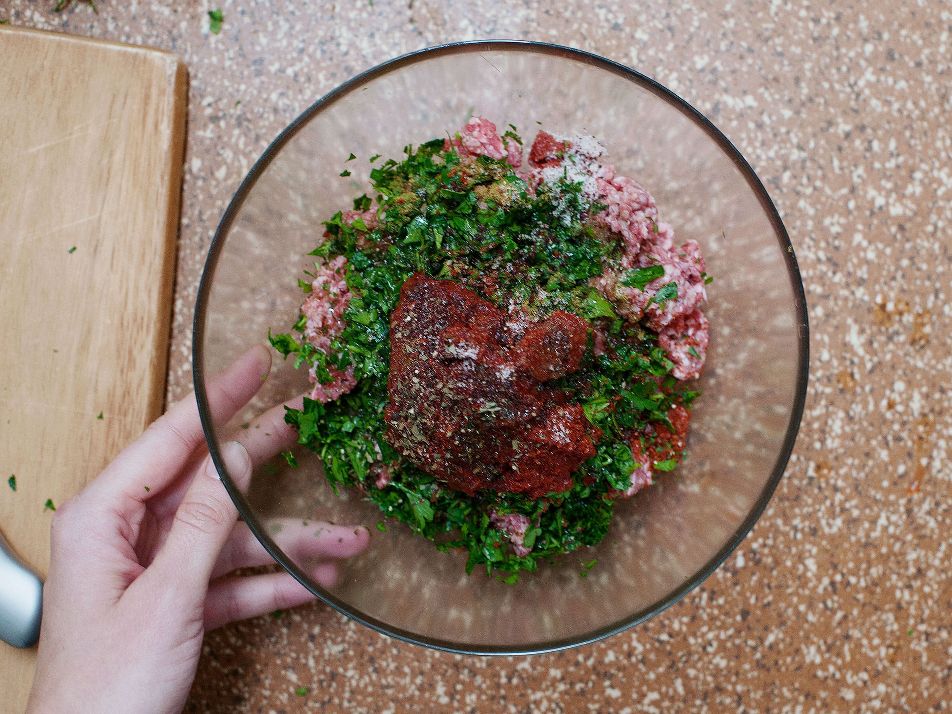 Finely chop flat leave parsley. Set half of it aside for garnish. In a large bowl, mix together minced lamb, diced tomatoes, half of the chopped parsley, tomato paste, garlic powder, garlic oil, crushed chili flakes, and cumin. Season with salt and pepper.