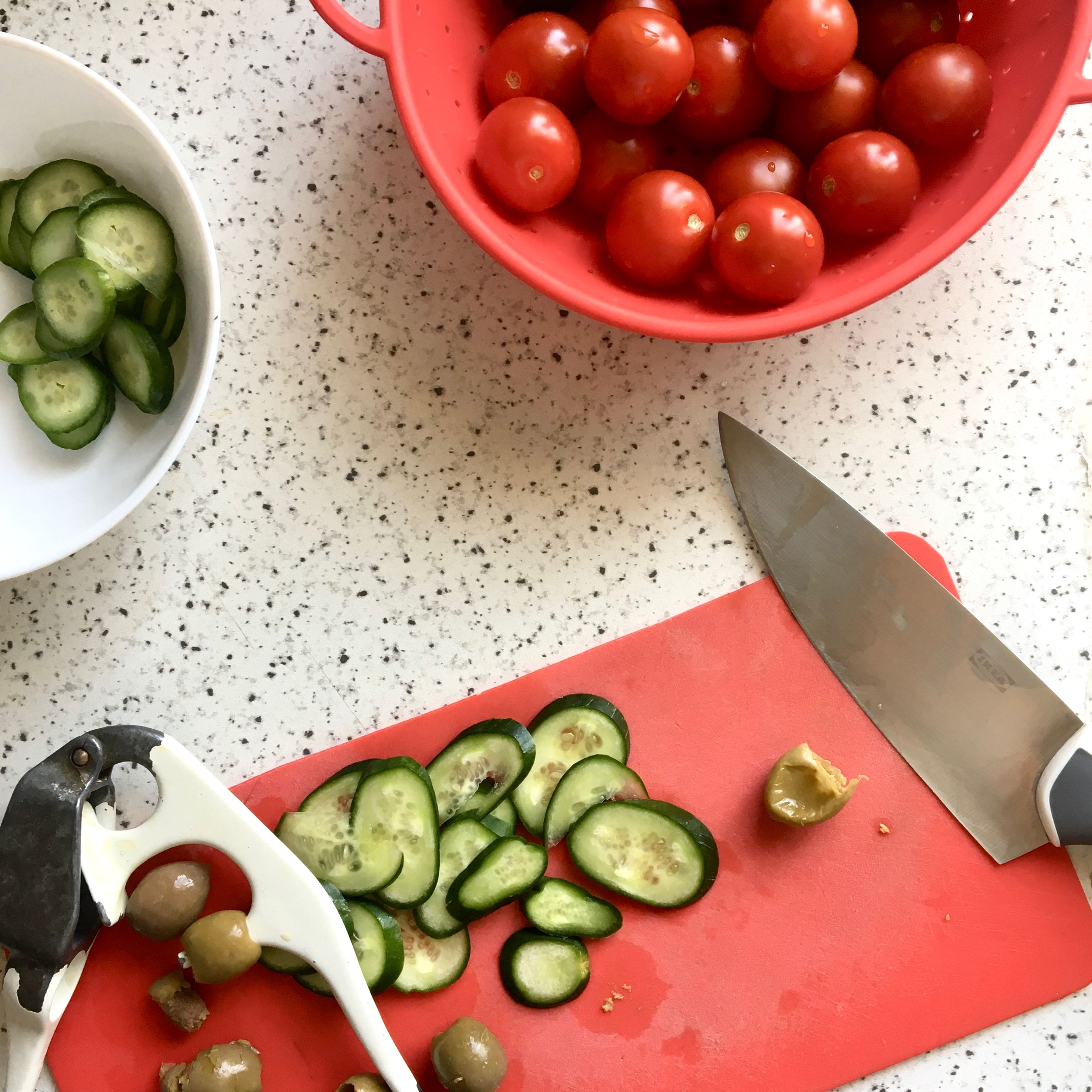 To prepare the topping, finely slice olives, onion, tomatoes and cucumbers. When the dough has risen, carefully transfer it onto a floured work surface and fold it from its four sides, just once from each side. Divide in two and cover again with damp cloth for their second rise, about 45 min. Lightly grease two baking sheets and set them aside. Heat the oven to 240 C.
