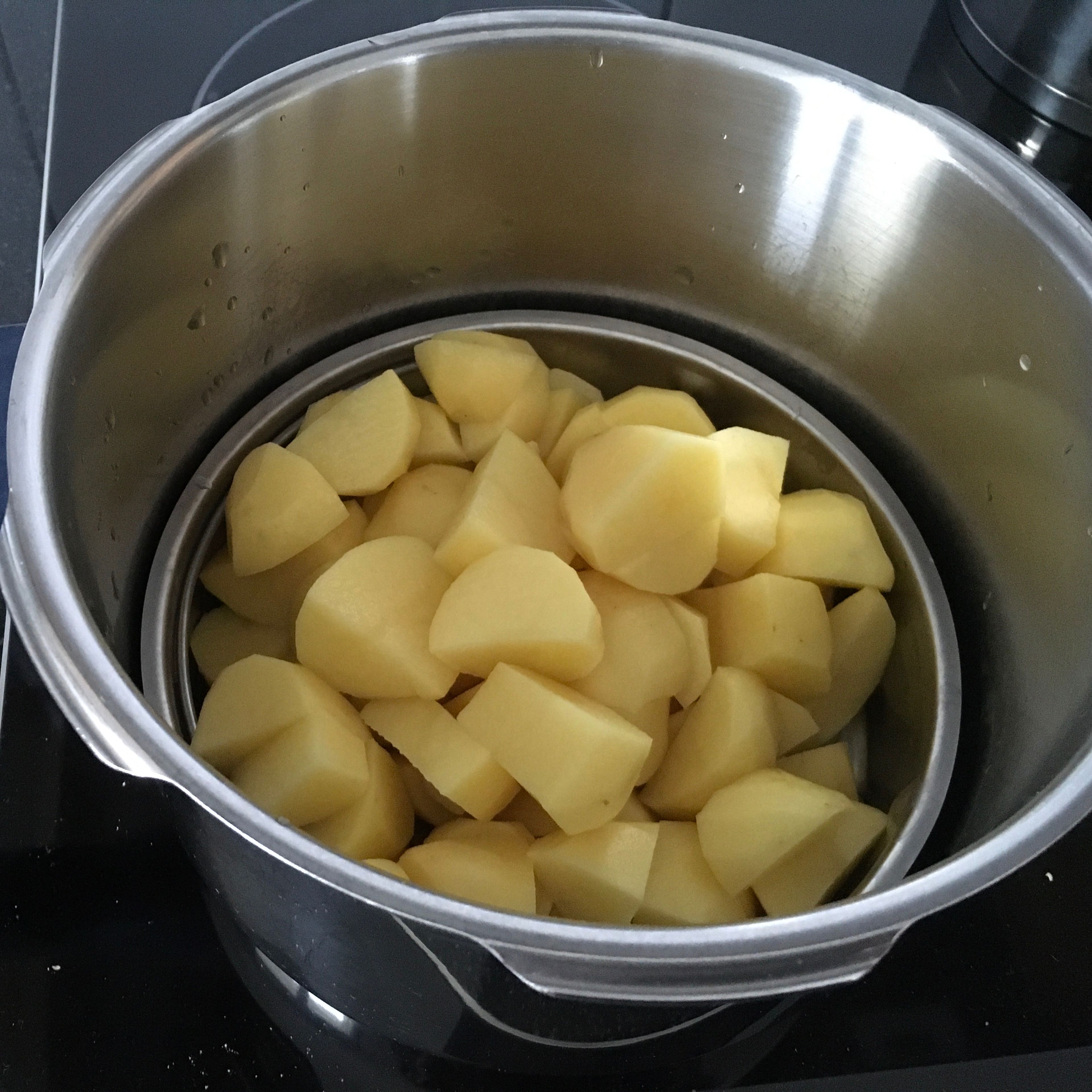 Schneide die Kartoffeln in Stücke und gib sie in den Dampfkocher.