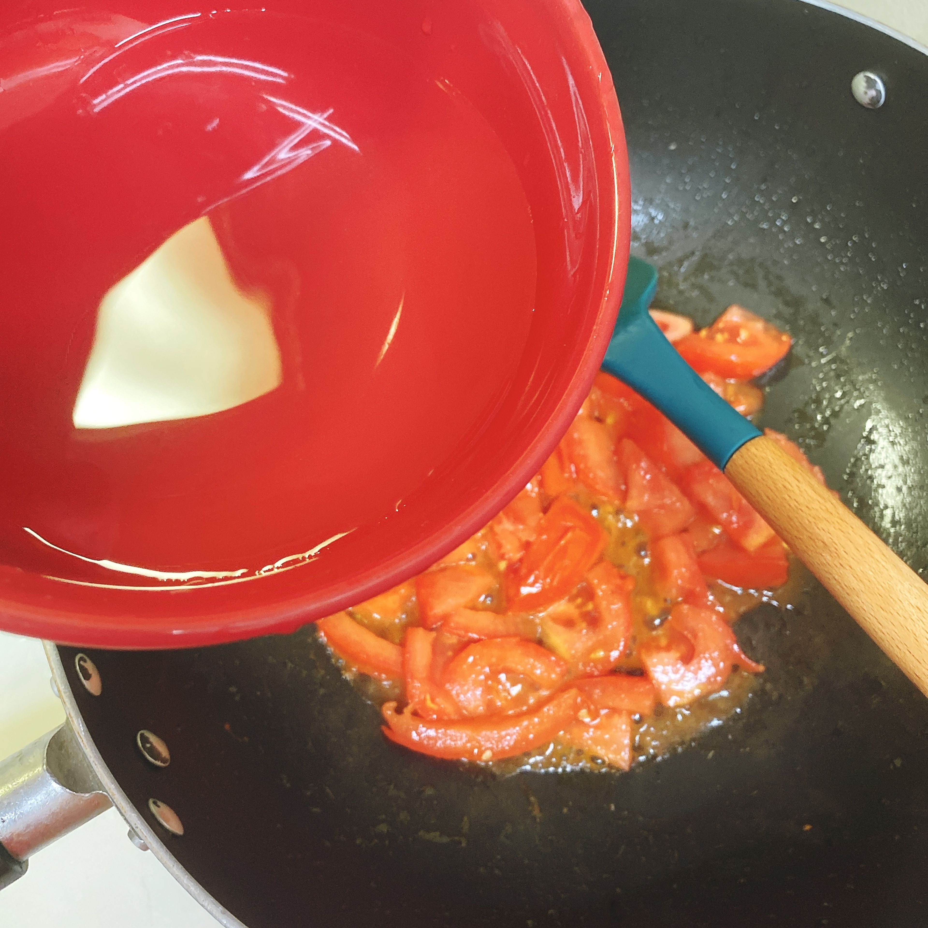 Dump the oil and no need to wash the pot. Use the residual to fry the tomato cubes until the juice is sucked out. Add half a bowl of water and wait until it boils to add the mushroom and fried tofu. Add sugar and ketchup and then put the lid on.