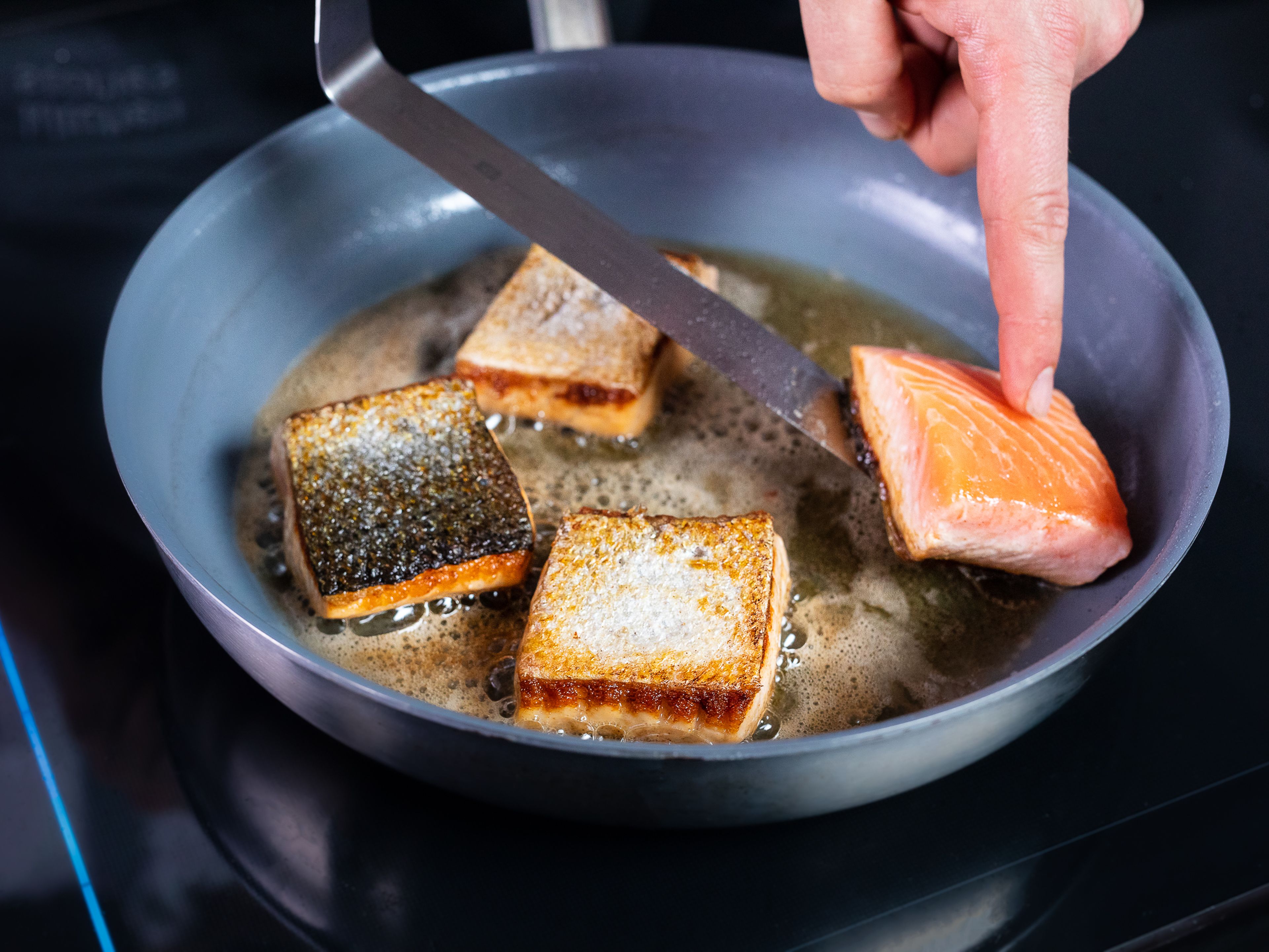 In einer Pfanne etwas Olivenöl bei mittlerer Hitze erhitzen. Sobald die Temperatur erreicht ist, die Lachsfilets mit der Hautseite nach unten in die Pfanne geben. Dann den Lachs mit Salz und Pfeffer würzen und die Butter dazugeben. Alles für ca. 3 – 5 Min. kochen lassen.