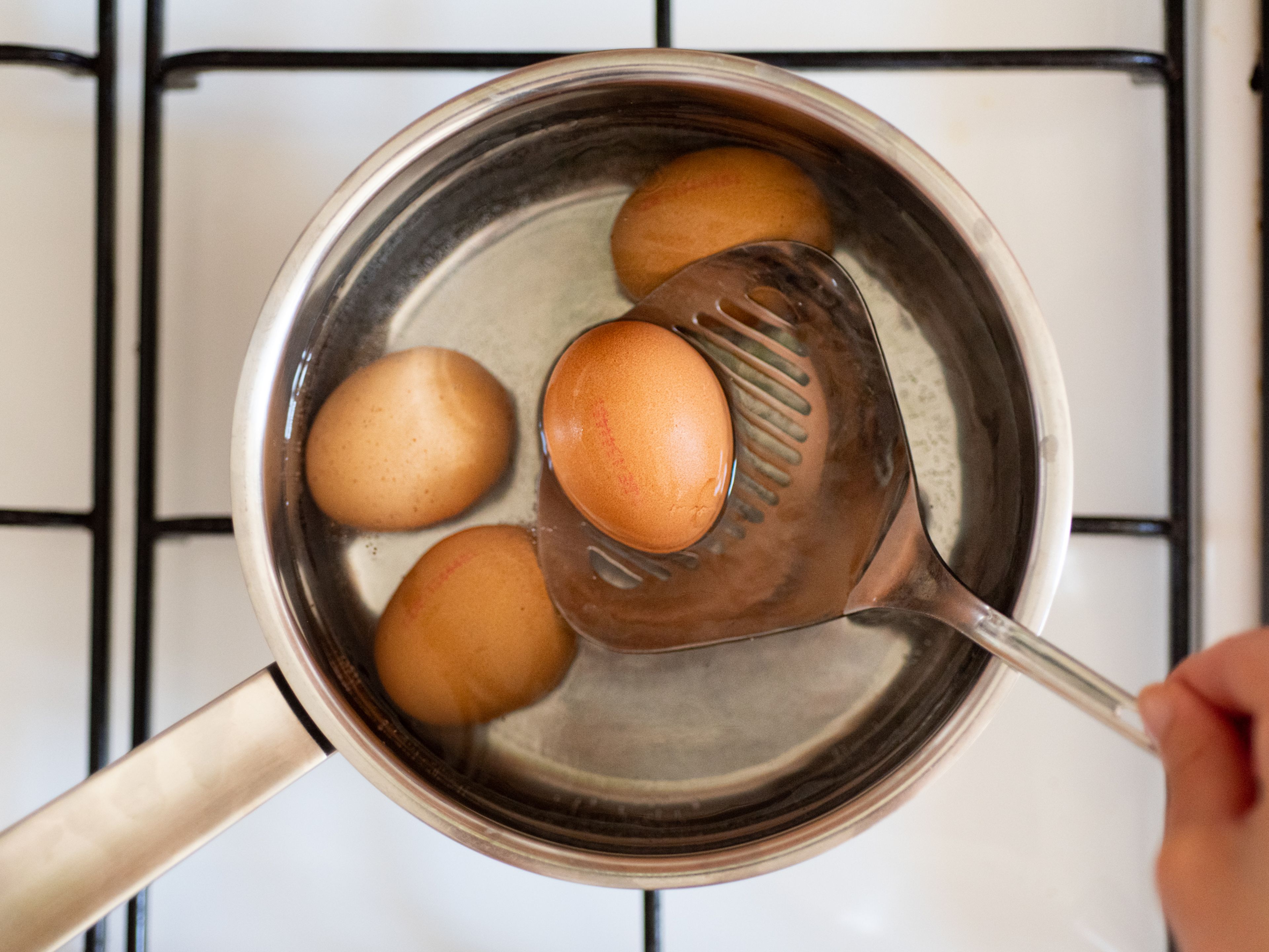 In der Zwischenzeit einen großen Topf mit Wasser bei mittlerer bis hoher Hitze zum Kochen bringen. Sobald das Wasser kocht, Eier hinzufügen. Die Eier ca. 7 - 8 Min. kochen, dann herausnehmen und unter fliessendem kaltem Wasser abschrecken. Sobald die Eier abgekühlt sind, schälen, in Scheiben schneiden und beiseite stellen.