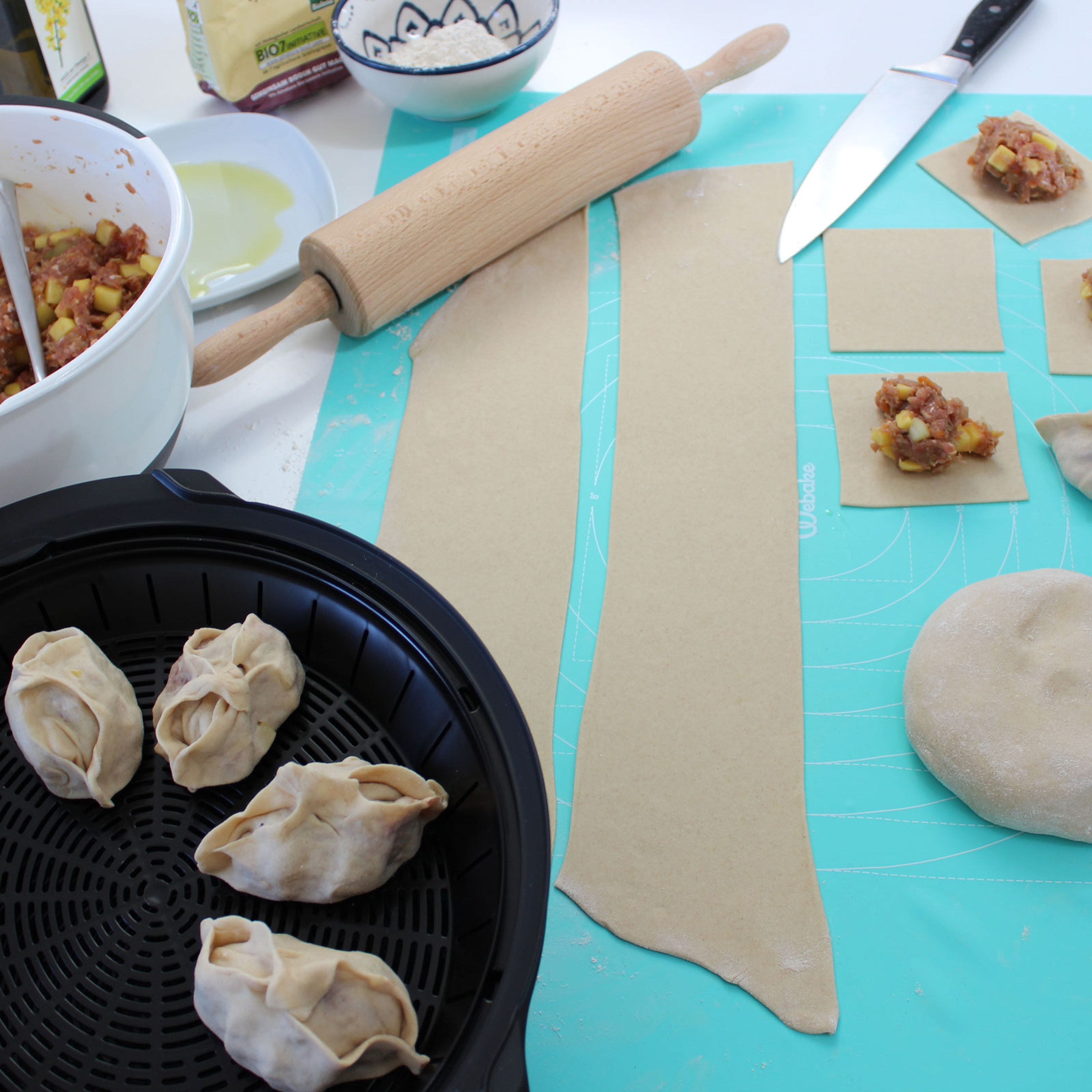 Auf einer leicht bemehlten Arbeitsfläche Teig dünn ausrollen, in Quadrate schneiden und mit der Masse füllen. Teigtaschen an den Ecken fassen und zusammendrücken, dann die Seiten und abschließend jeweils zwei Ecken zusammenfügen. Den Boden der Teigtaschen mit etwas Öl benetzen und in den Cookit Dampfgaraufsatz setzen.