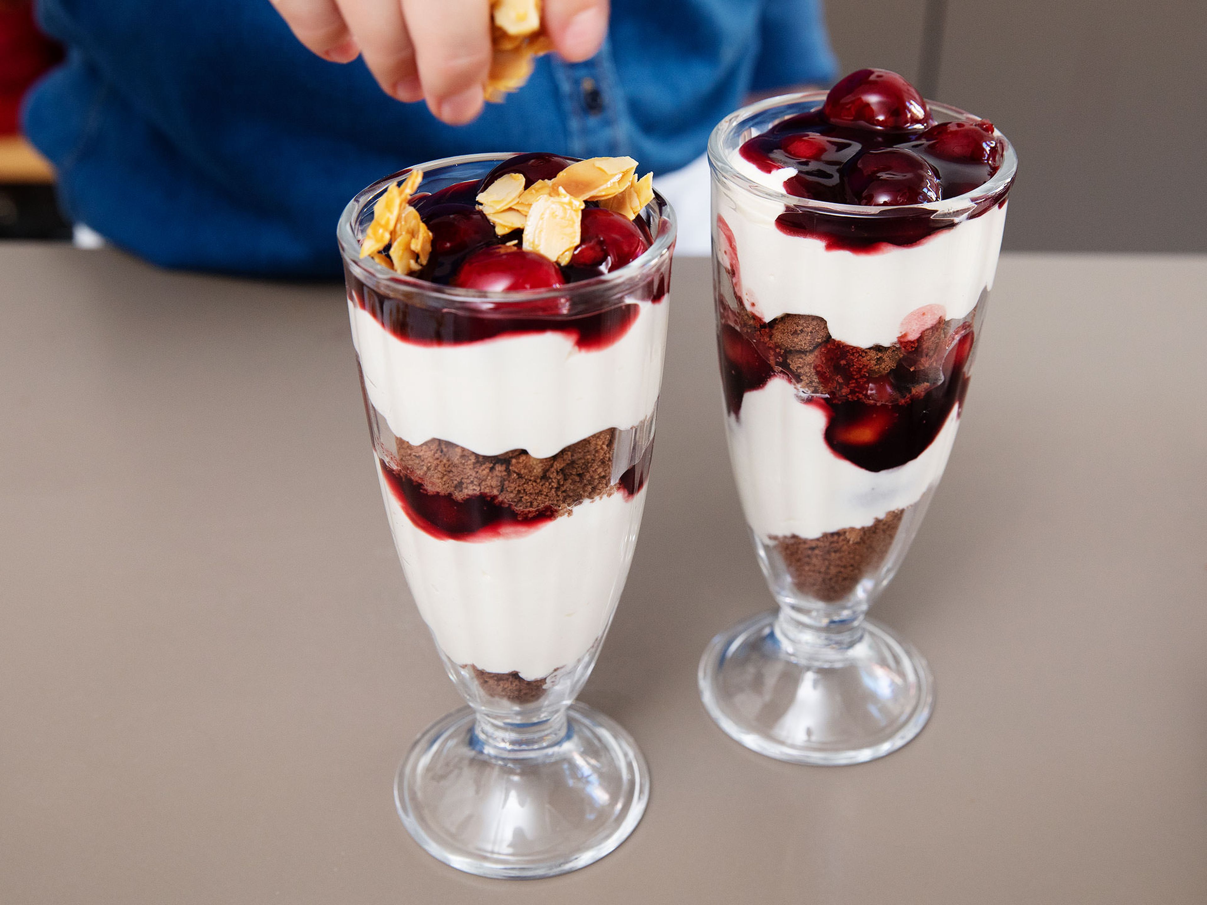 To serve, spoon layers of crumbled chocolate cookies, cream, and cherries to tall glasses. Continue with another set of layers and finish with the caramelized almonds. Enjoy!