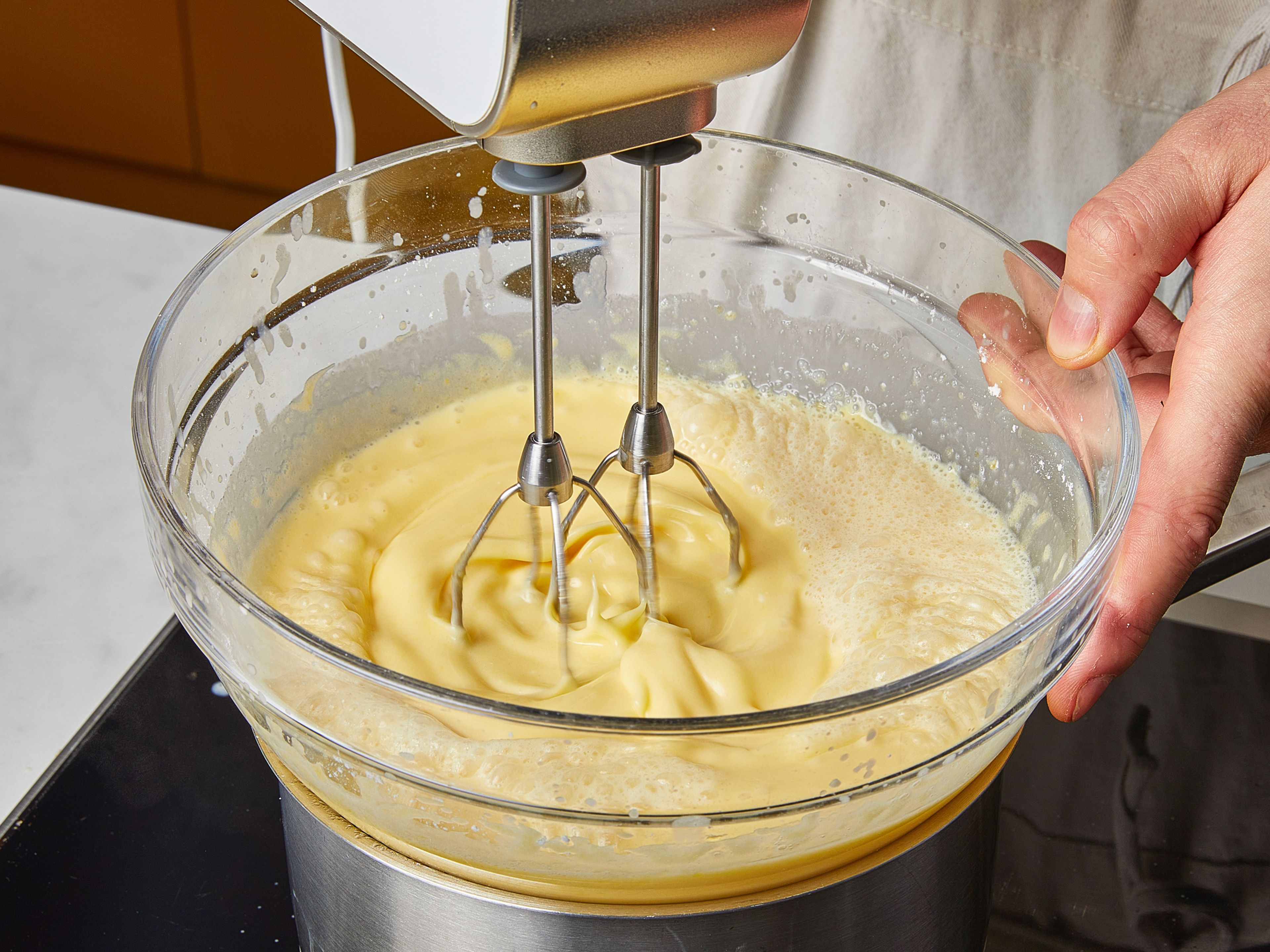 Remove the bowl from the pot. Add heavy cream and evaporated milk. Then place the bowl back on the water bath and continue whisking until the temperature reaches approx. 65–75°C (149–167°F), making sure again that the egg yolks do not curdle. Then add the rum and stir in well.