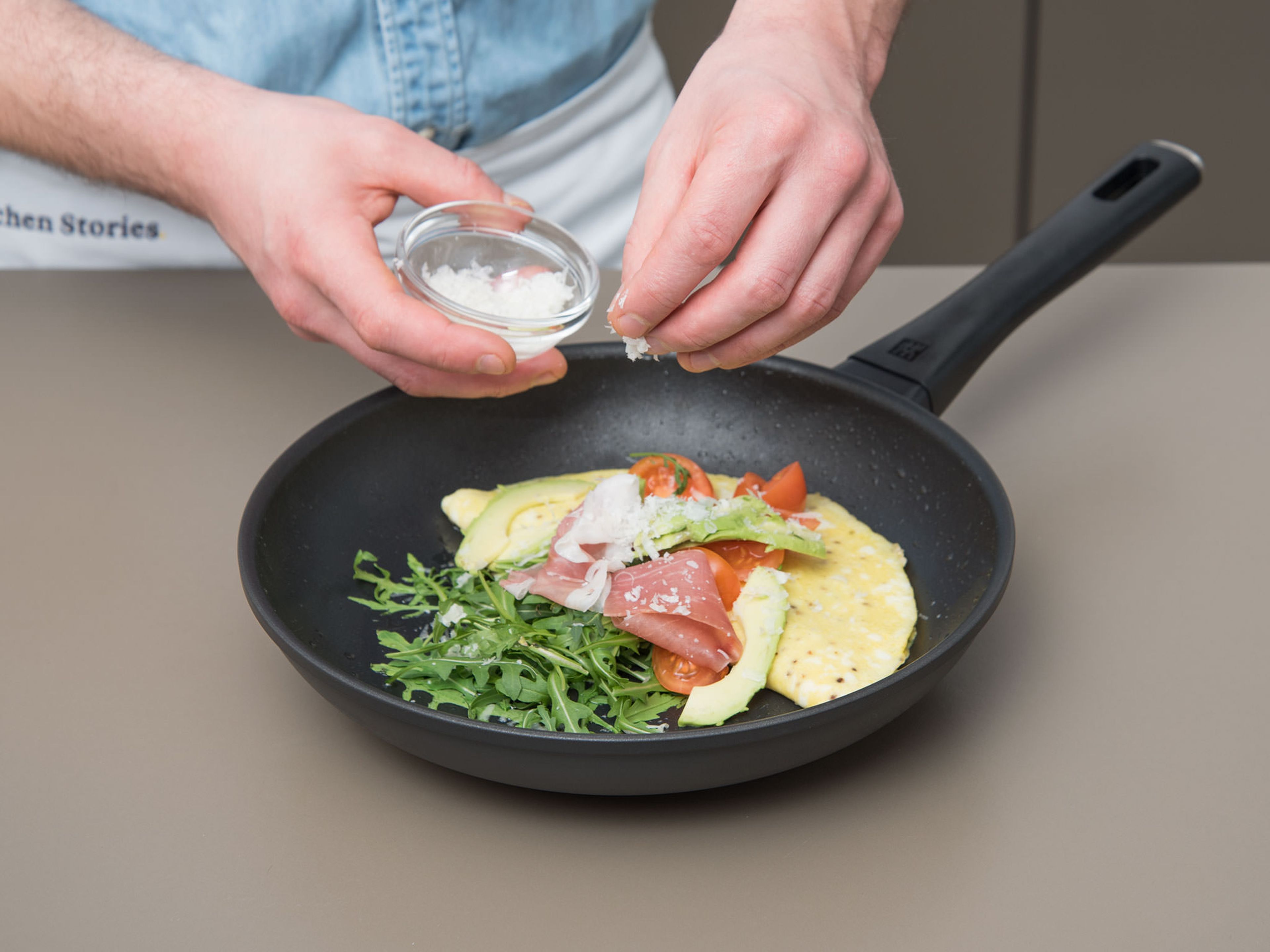 Pfanne vom Herd nehmen. Omelett mit Rucola, Tomaten, dem übrigen Prosciutto und Avocado anrichten. Mit Parmesan garnieren und sofort genießen!