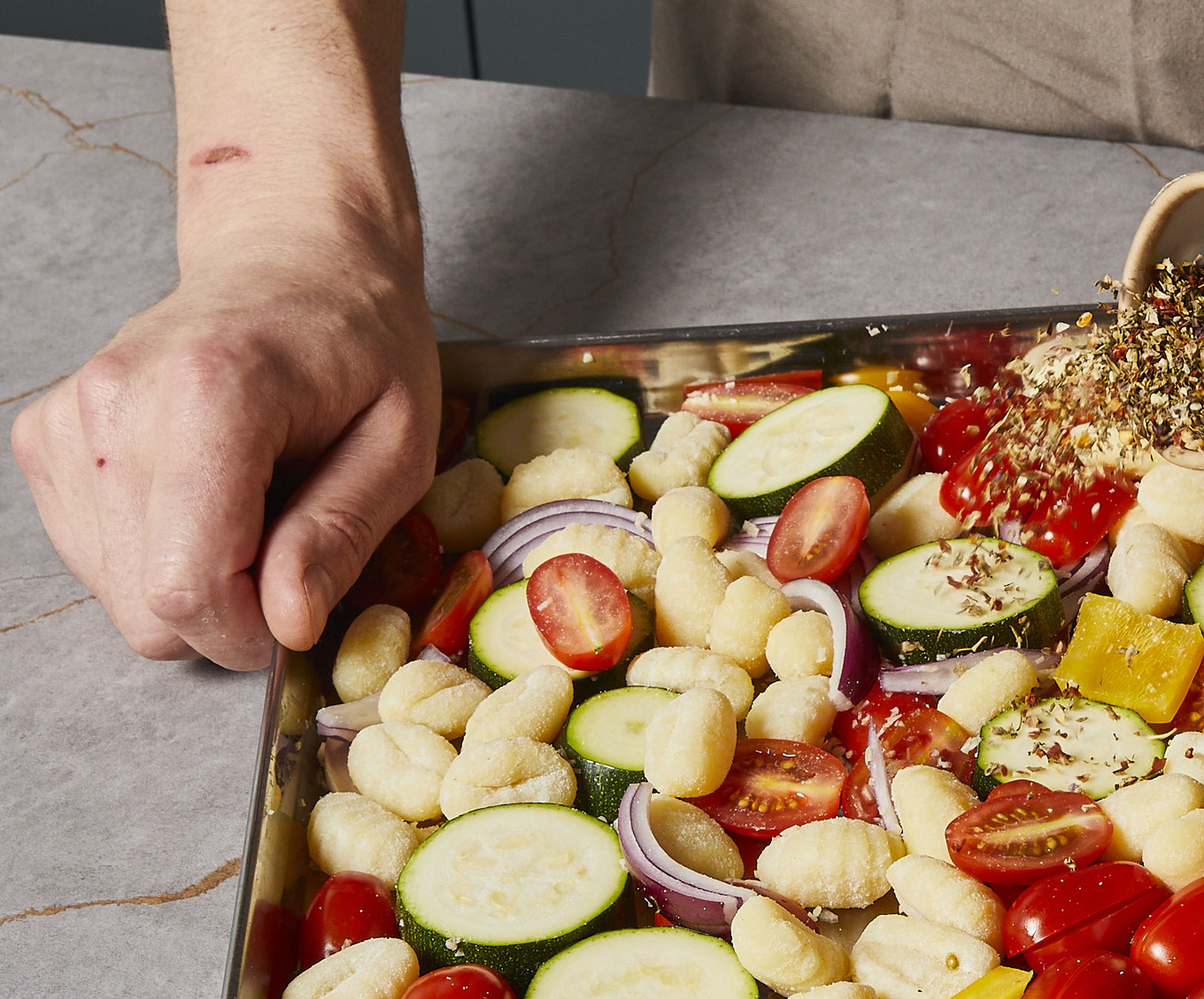 Gnocchi, Zwiebel, Zucchini, Paprika und Kirschtomaten auf einem mit Airfryer-Backpapier ausgelegten Liner verteilen. Den Knoblauch darüberpressen. Getrocknetes Basilikum, Thymian, Oregano und Chiliflocken darüberstreuen, mit der Hälfte des Olivenöls und Balsamico beträufeln. Mit Salz und Pfeffer würzen, alles gut vermengen und bei 180°C ca. 15–20 Min. im Airfryer backen. Zwischendurch zweimal durchmischen.