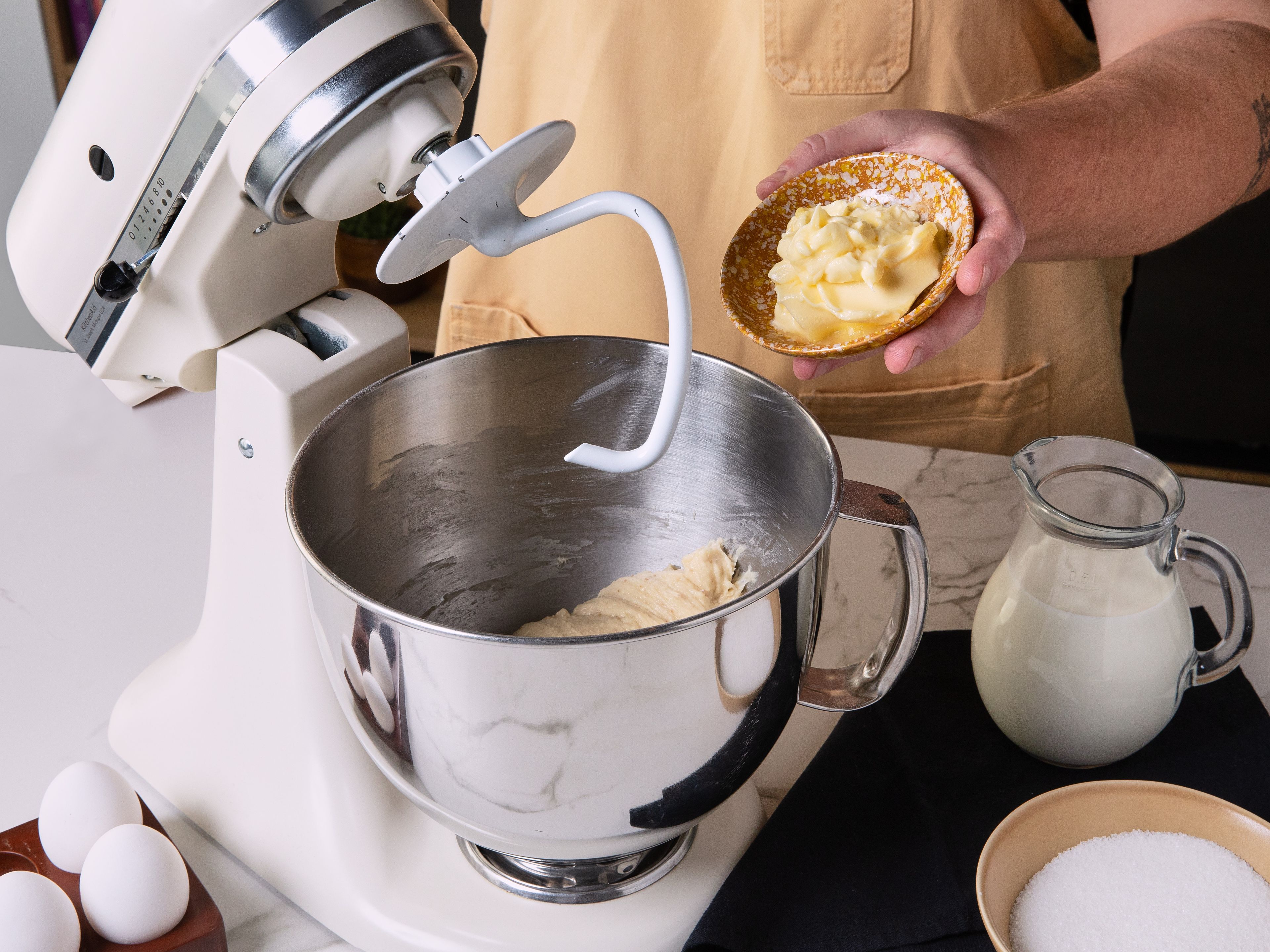 Mehl, Trockenhefe und Salz in eine Rührschüssel oder die Schüssel einer Küchenmaschine geben und mit den Knethaken vermengen. Lauwarme Milch mit Ei und Zucker verquirlen, zur Mehlmischung geben und auf niedriger Stufe kneten, bis sich alles verbindet. Ungefähr die Hälfte der weichen Butter hinzufügen und weiterkneten, bis ein glatter, elastischer Teig entsteht. Abdecken und an einem warmen Ort ca. 1 Std. gehen lassen, bis sich das Volumen deutlich vergrößert hat.