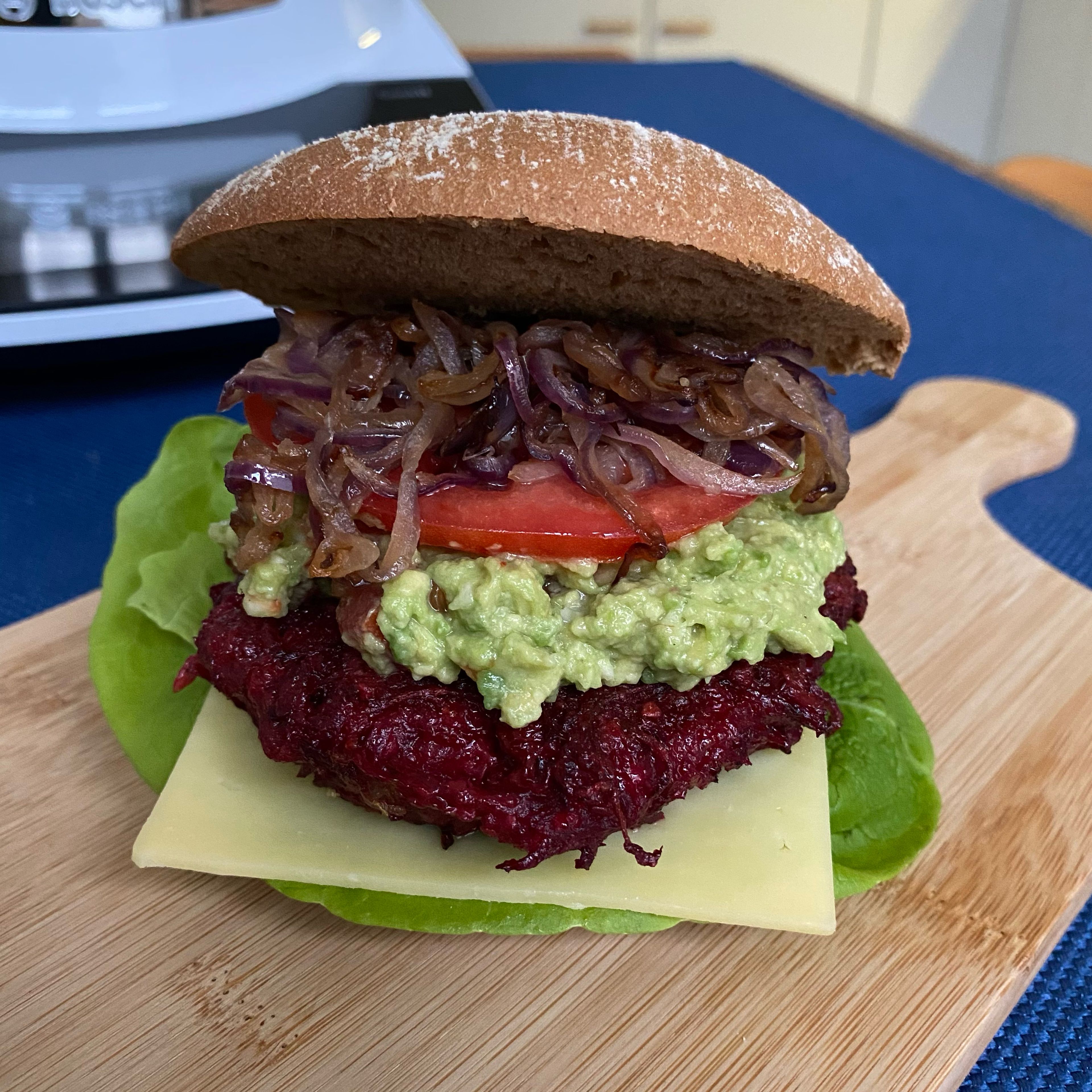 Jetzt geht es ans Stapeln. Die aufgebackenen Burgerbrötchen mit Salat, Cheddar, Patty, Guacamole, Tomate und Zwiebeln belegen und den Burger schnell genießen!