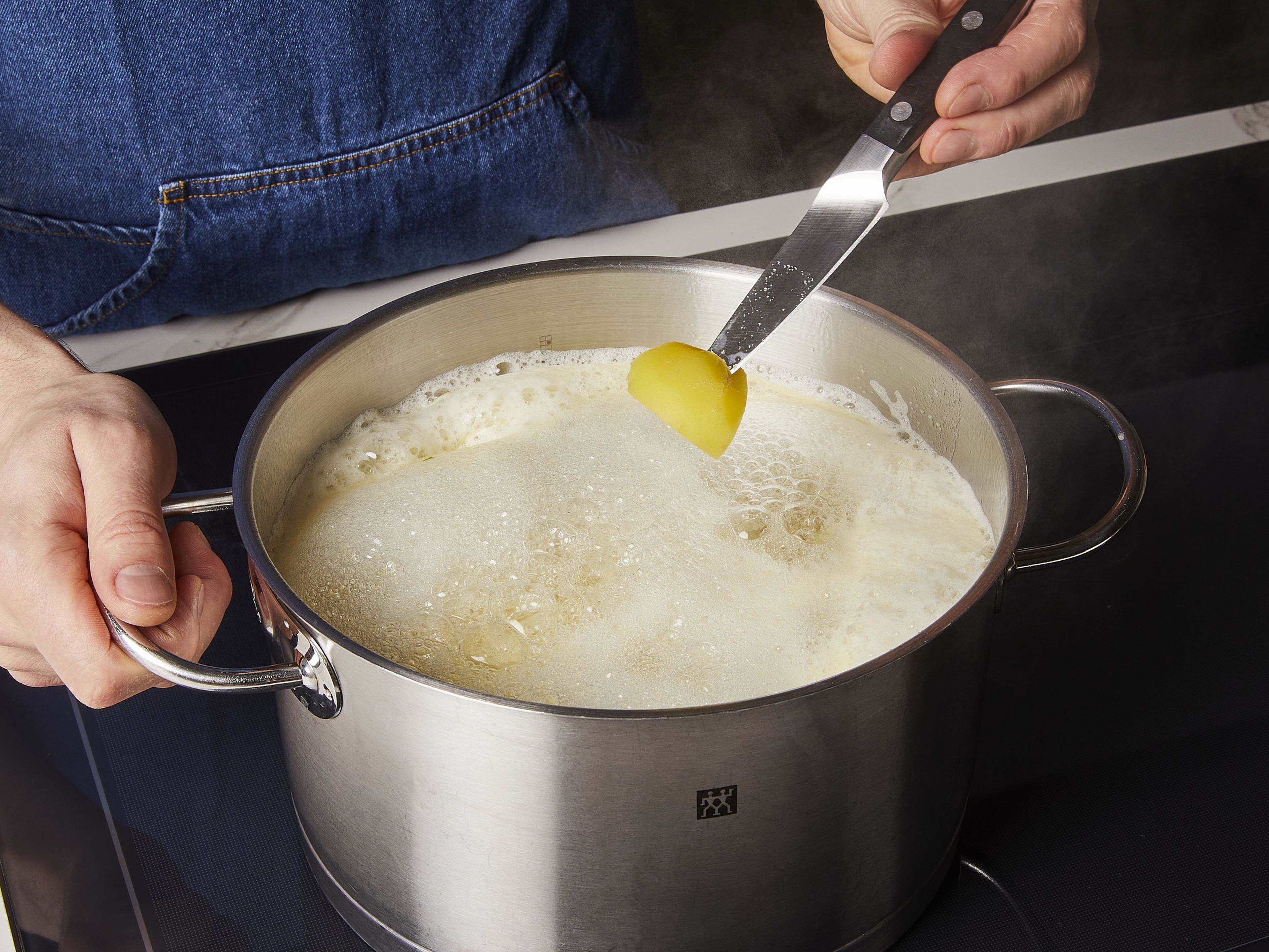 Den Backofen auf 220°C bei Ober-Unterhitze oder 200°C bei Umluft vorheizen. Die Kartoffeln schälen und in ca. 4–5 cm große Stücke schneiden. Zwei Liter Wasser in einem großen Topf bei starker Hitze zum Kochen bringen. Salz, Backnatron und Kartoffeln hinzufügen und umrühren. Noch einmal aufkochen lassen, dann die Hitze auf Köcheln reduzieren. Ca. 10 Min. kochen, bis die Kartoffeln beim Einstechen mit einem Messer weich sind.