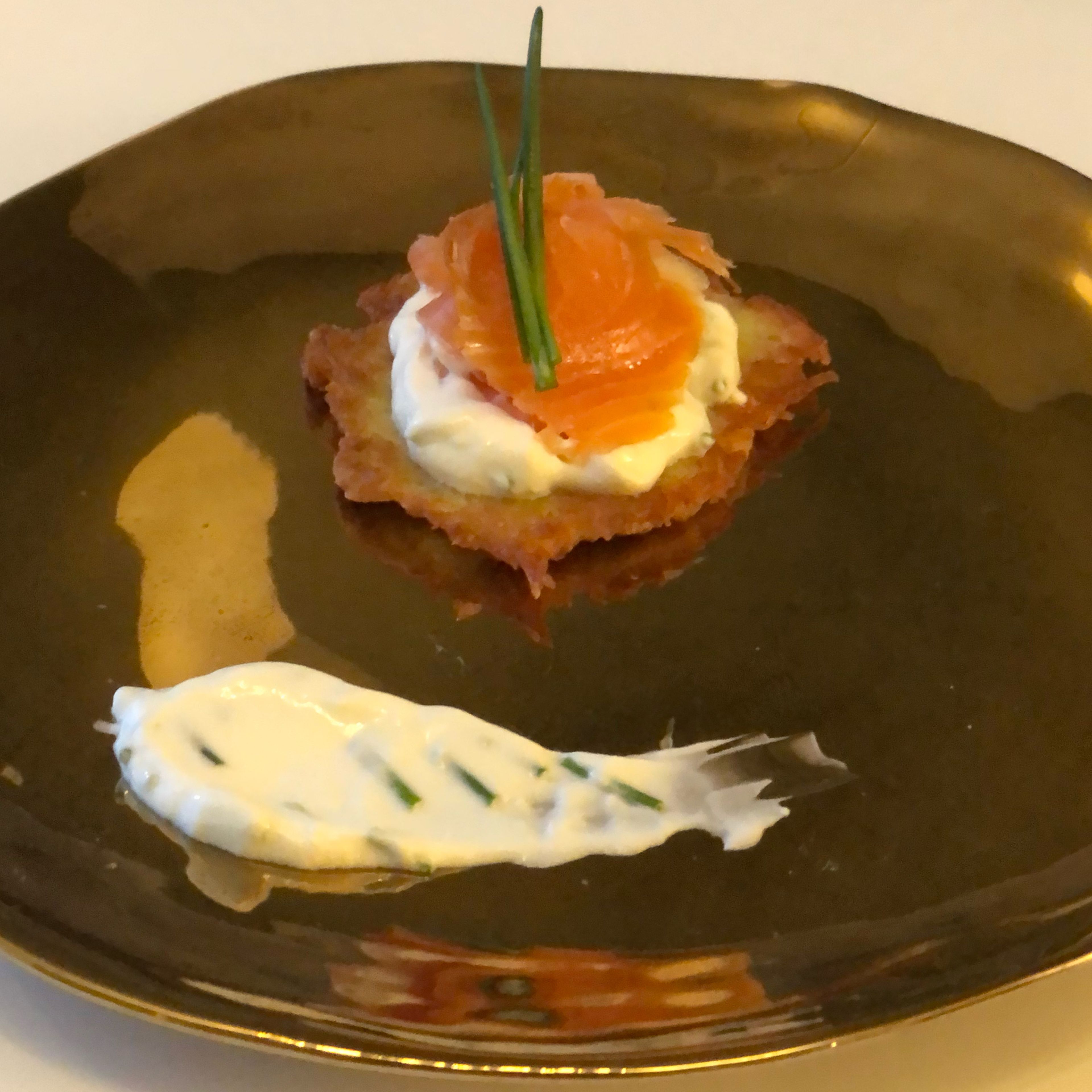Place a rösti on a plate. Put on some sauce and finish of with some smoked salmon and chives.