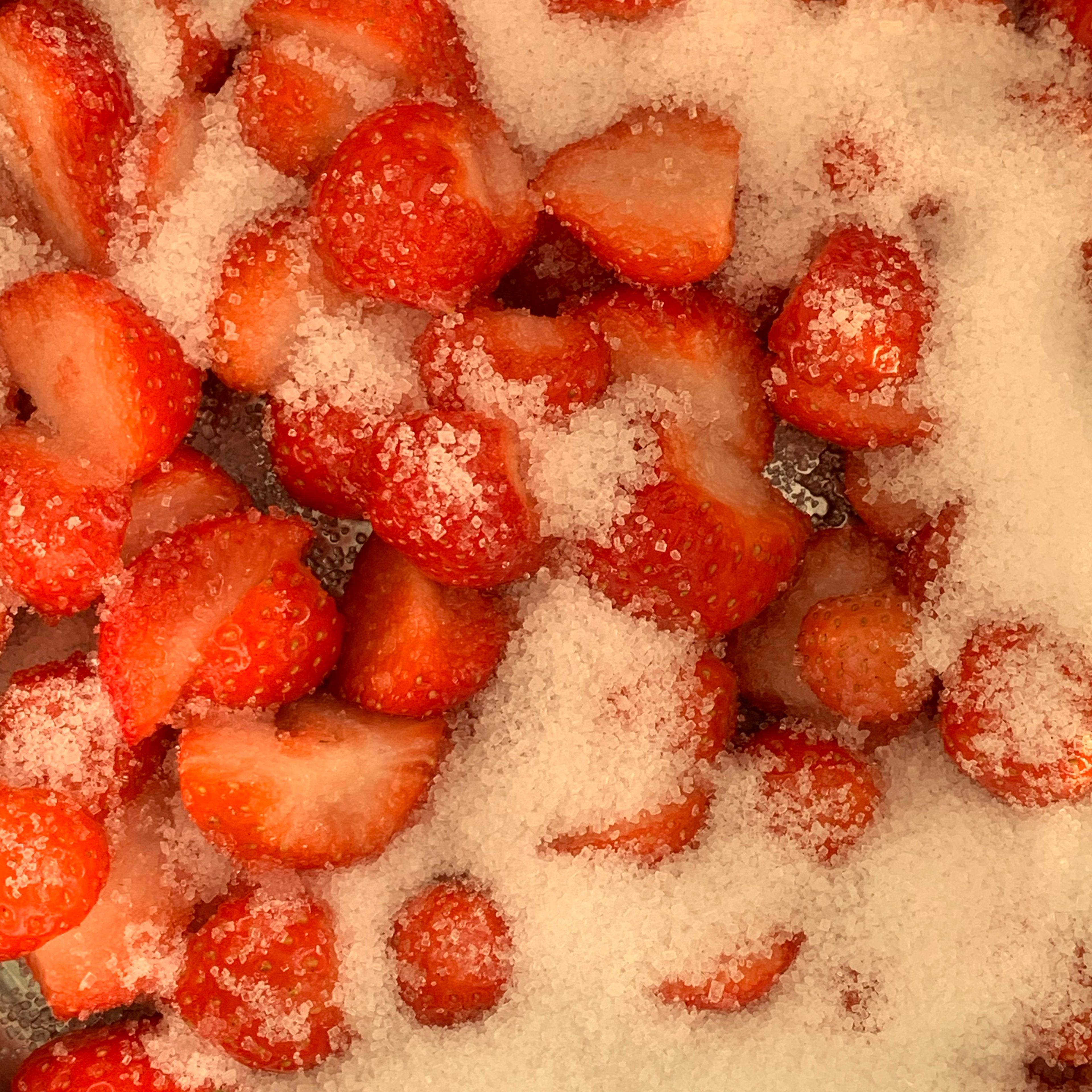 Clean and halve the strawberries. Add sugar.