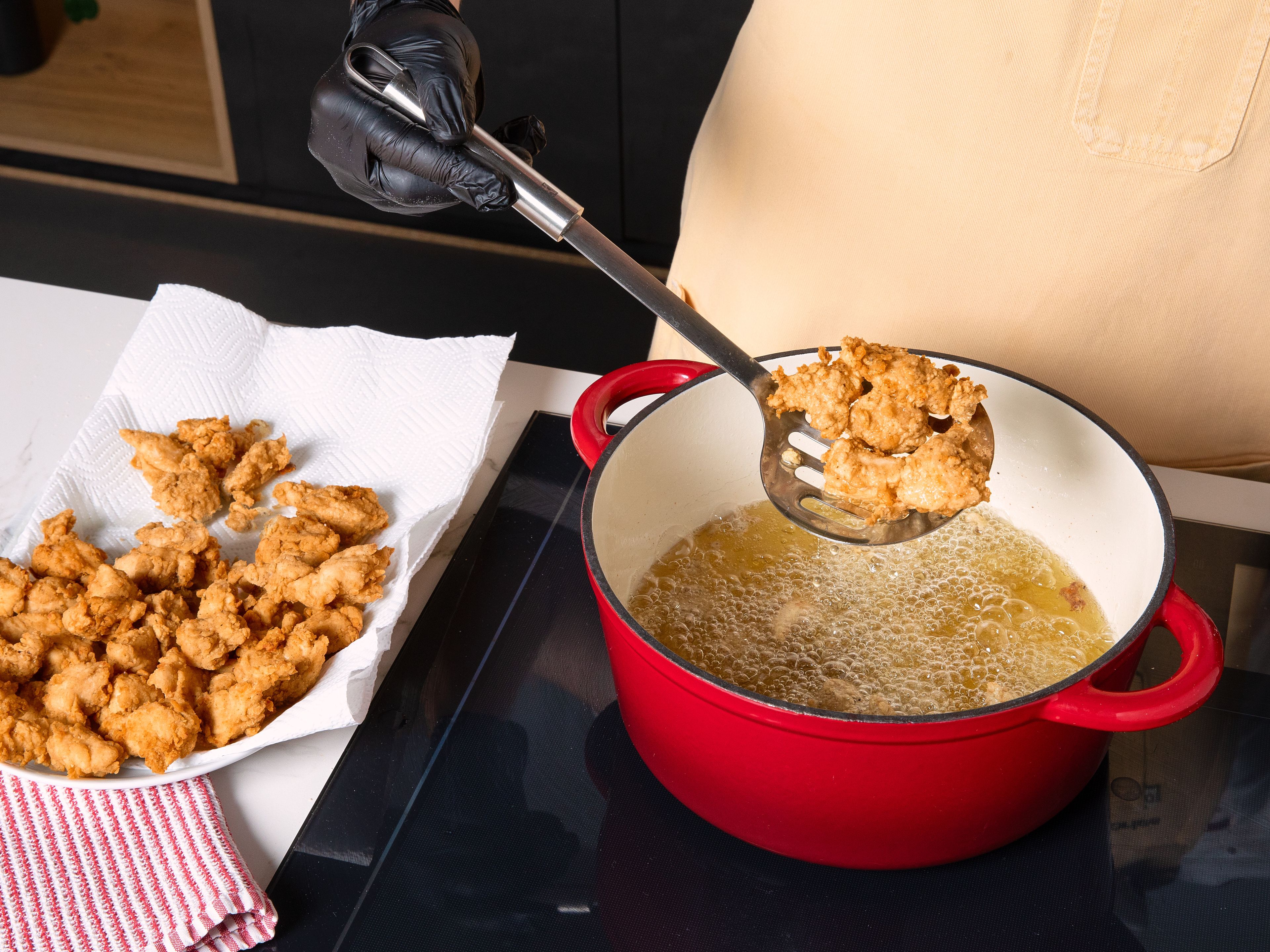 Das Hähnchen aus der Marinade nehmen und im gewürzten Mehl wenden, bis jedes Stück gleichmäßig damit bedeckt ist. Das überschüssige Mehl in einem Sieb vorsichtig abschütteln. Sobald das Öl eine Temperatur von 190°C erreicht hat, die Hälfte des Hähnchens hineingeben und für ca. 2 Min. frittieren. Mit einem Schaumlöffel herausheben, abtropfen lassen und auf einen mit Küchenpapier ausgelegten Teller geben. Sofort mit etwas Salz bestreuen. Das Öl erneut auf 190°C erhitzen und den Vorgang mit der restlichen Portion wiederholen. Das fertige Popcorn Chicken zusammen mit Pommes und einem Dip nach Wahl servieren.