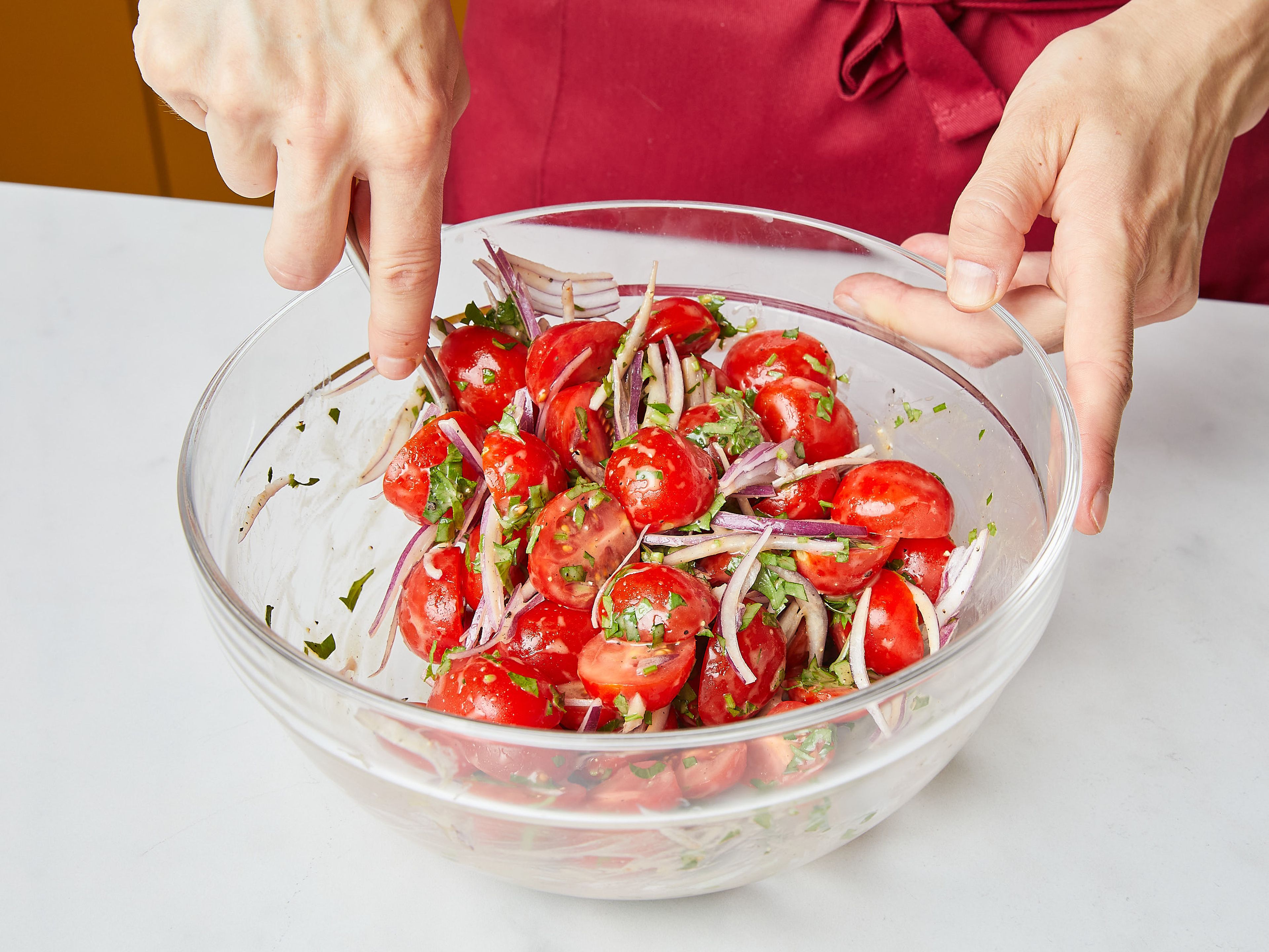 Die Hälfte des Dressings mit der Tomaten-Zwiebel-Mischung vermengen und auf die Platte über den Salat geben.